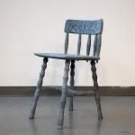 Old wooden chair with a simple design, placed against a plain wall