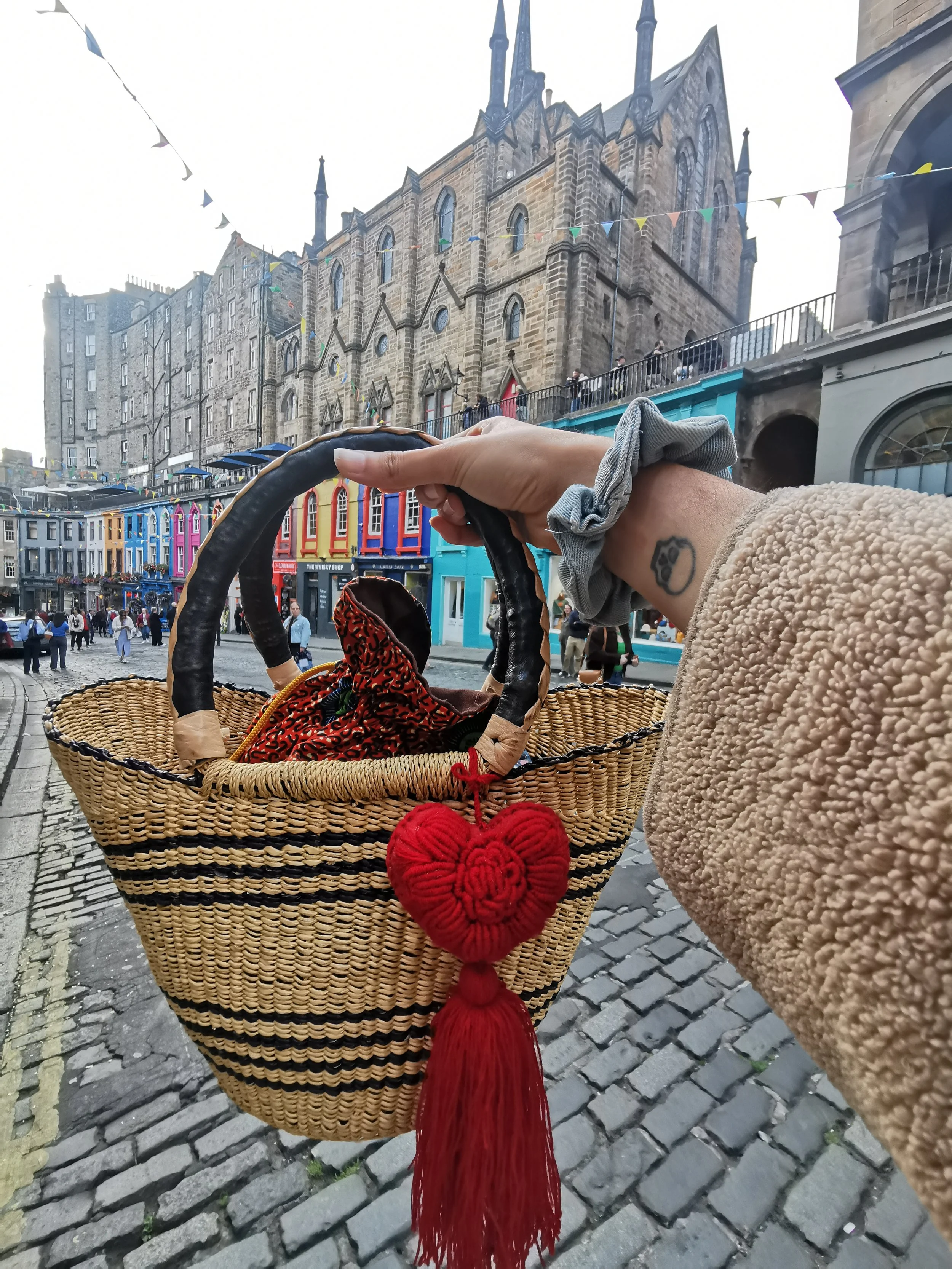 Handcrafted red heart charm with tassel, made by Mexican artisans, displayed on a woven basket