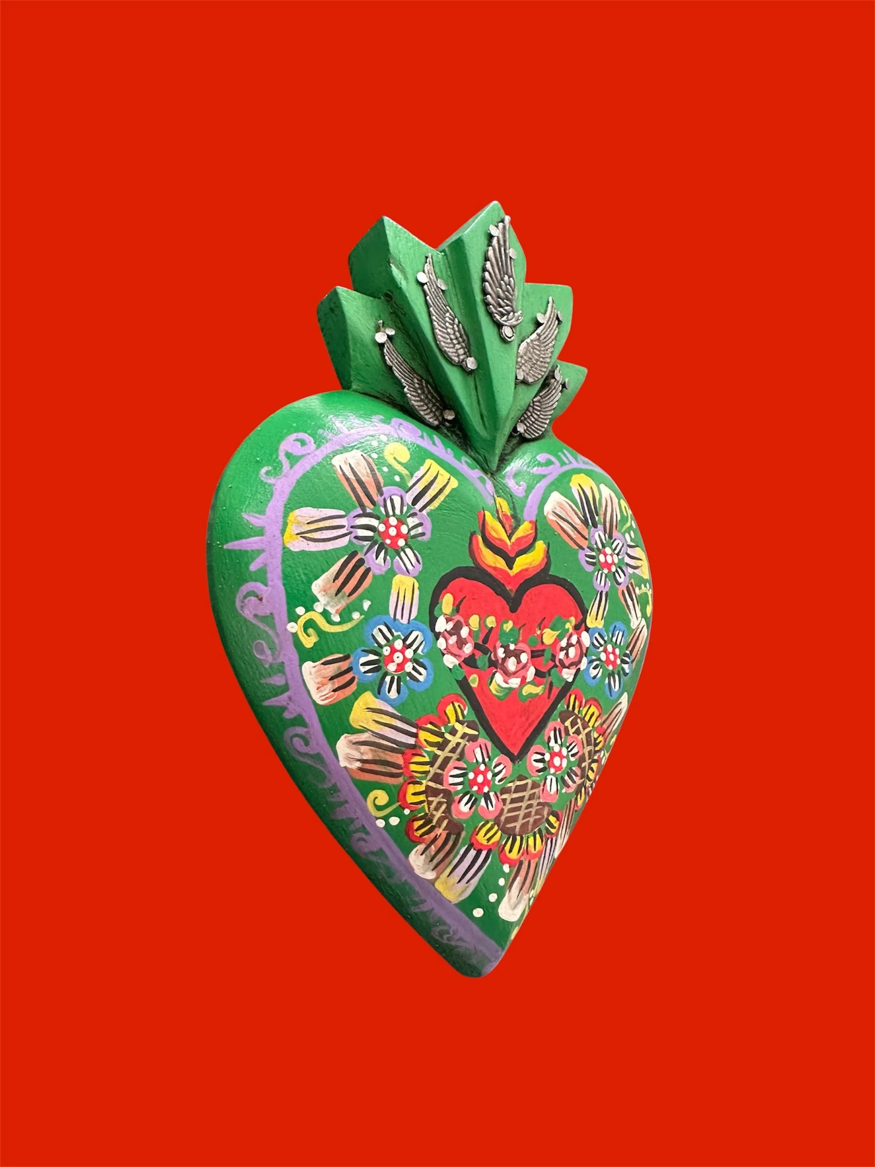 Close-up detail of Mexican milagrito heart sacred heart green.