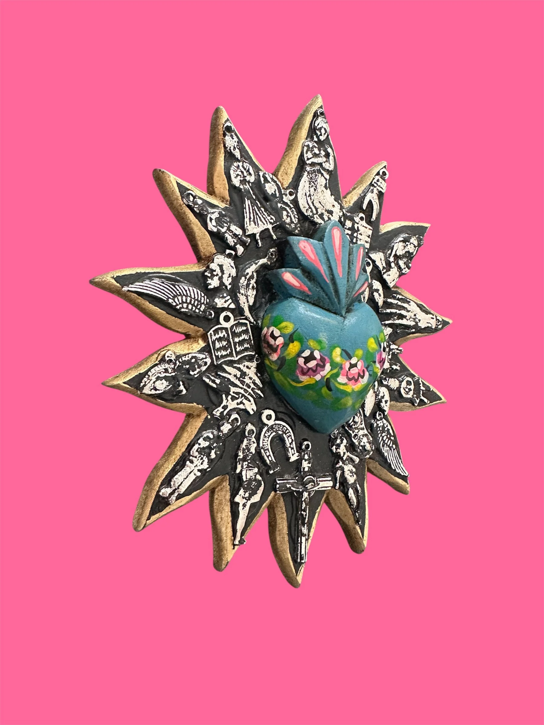 Close-up detail of blue sunburst milagrito featuring traditional Mexican folk art design.