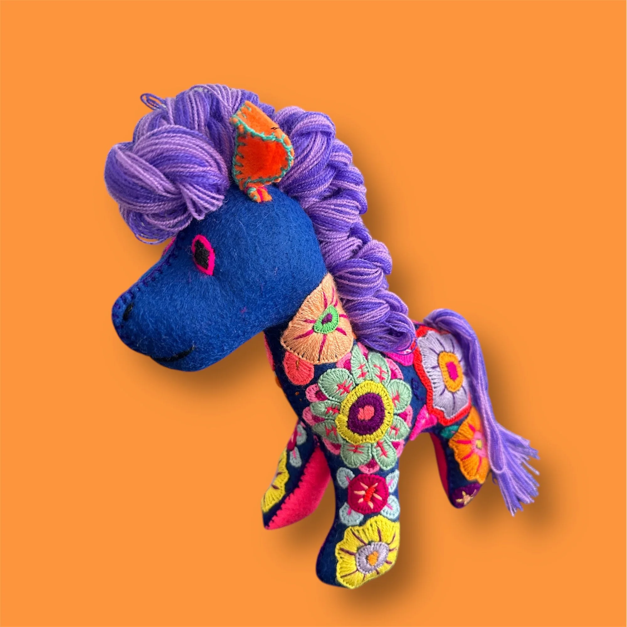 Close-up detail of blue embroidered horse soft toy with traditional Mexican stitching.