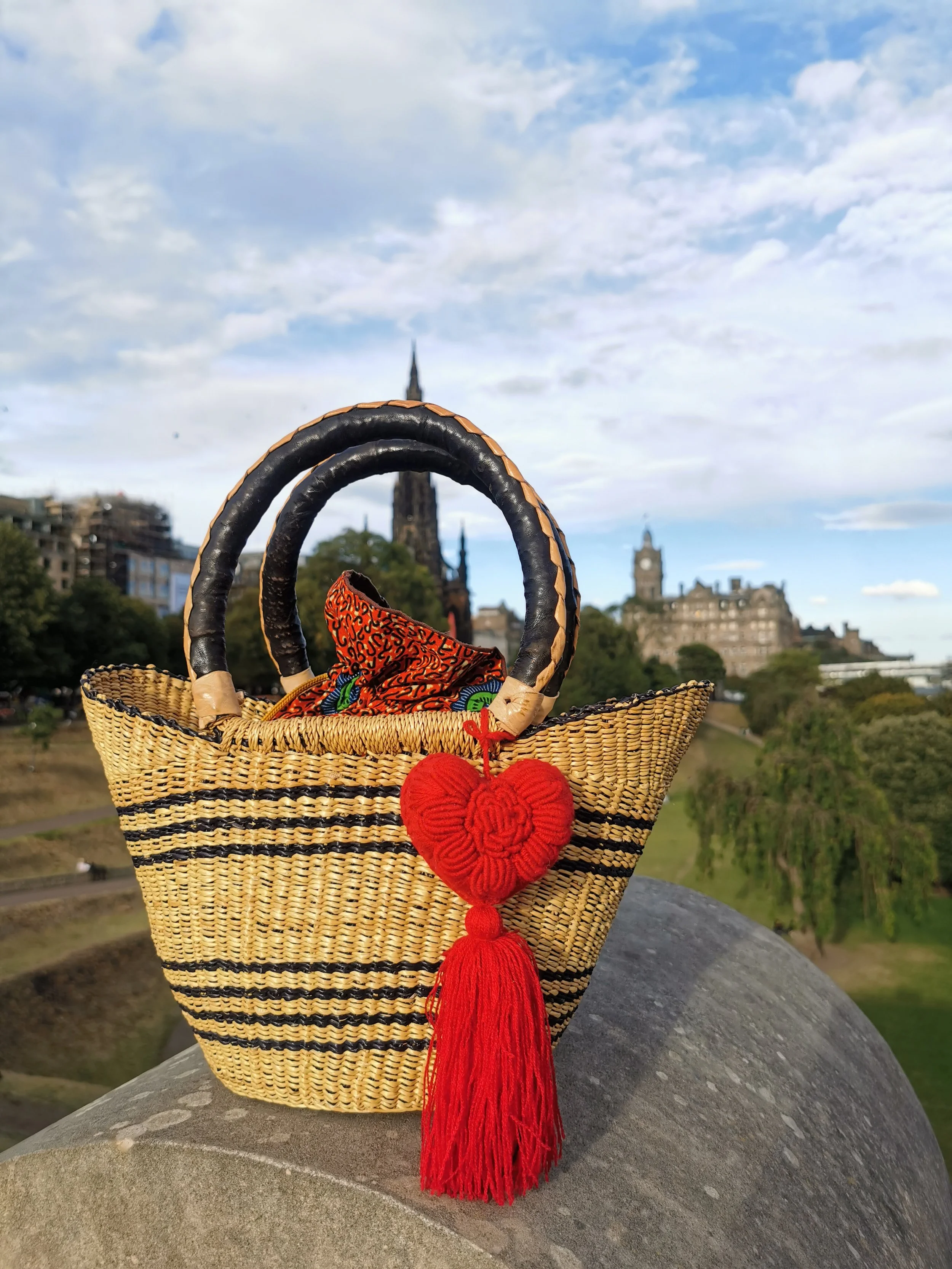 Handcrafted red heart charm with tassel, made by Mexican artisans, displayed on a woven basket
