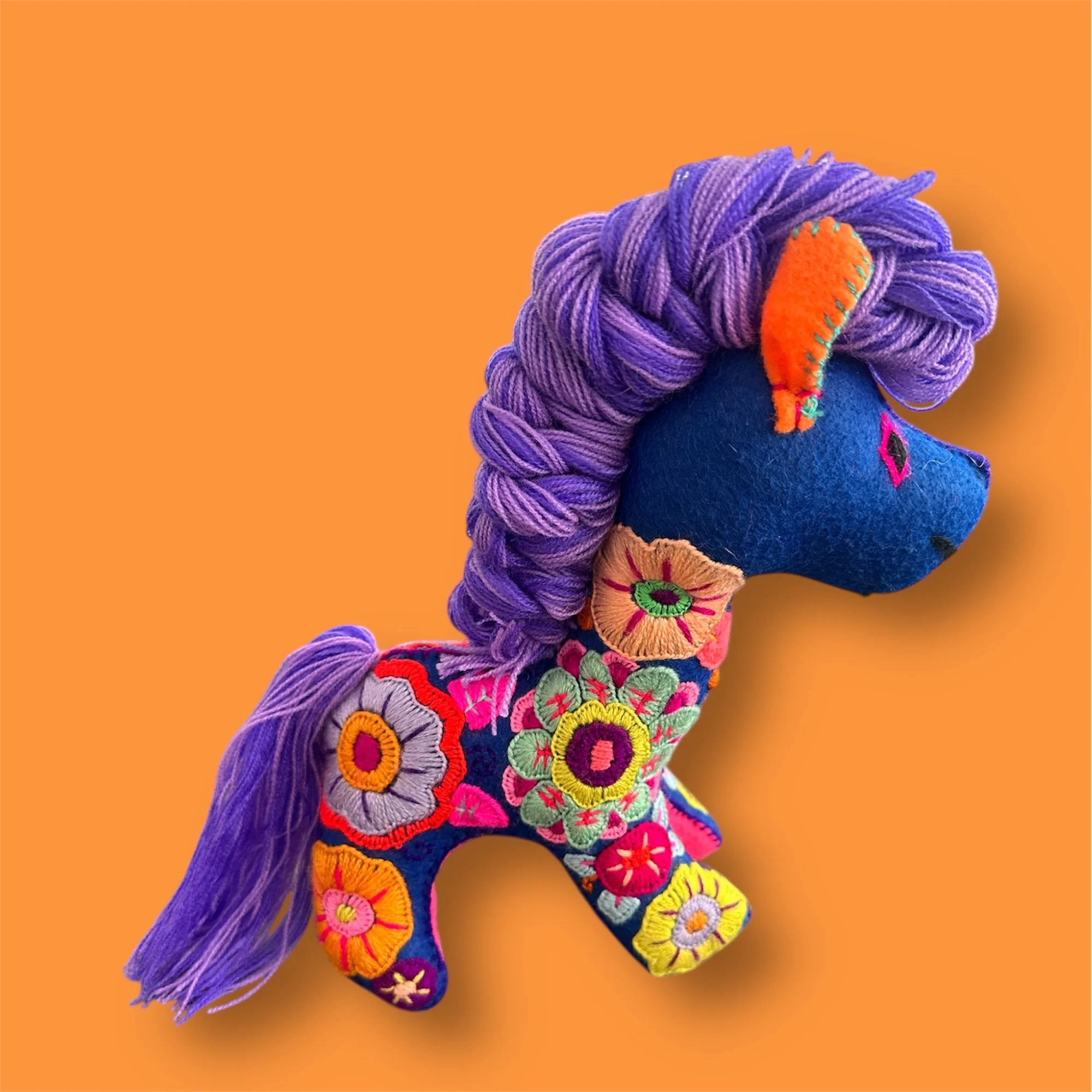 Side view of blue embroidered horse soft toy handmade in Mexico.