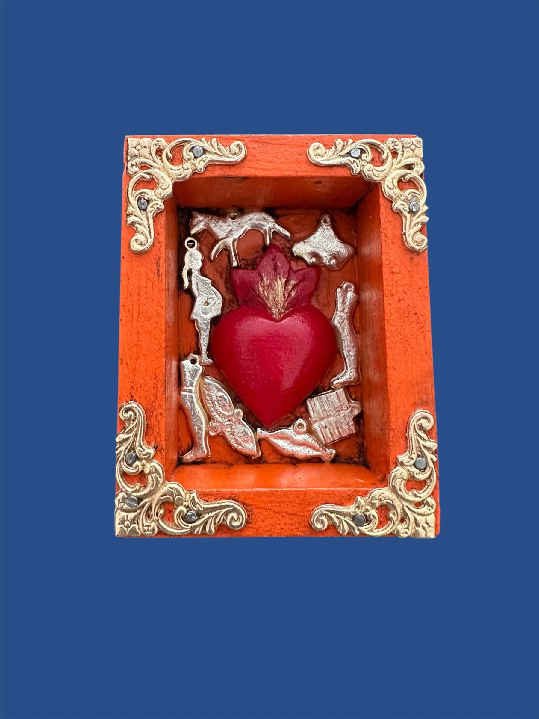 Close-up detail of Mexican nicho featuring a traditional milagrito heart and folk art elements.