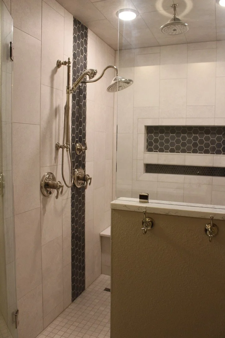 Large format tile and a built in niche organize essentials with a rain shower upgrade.