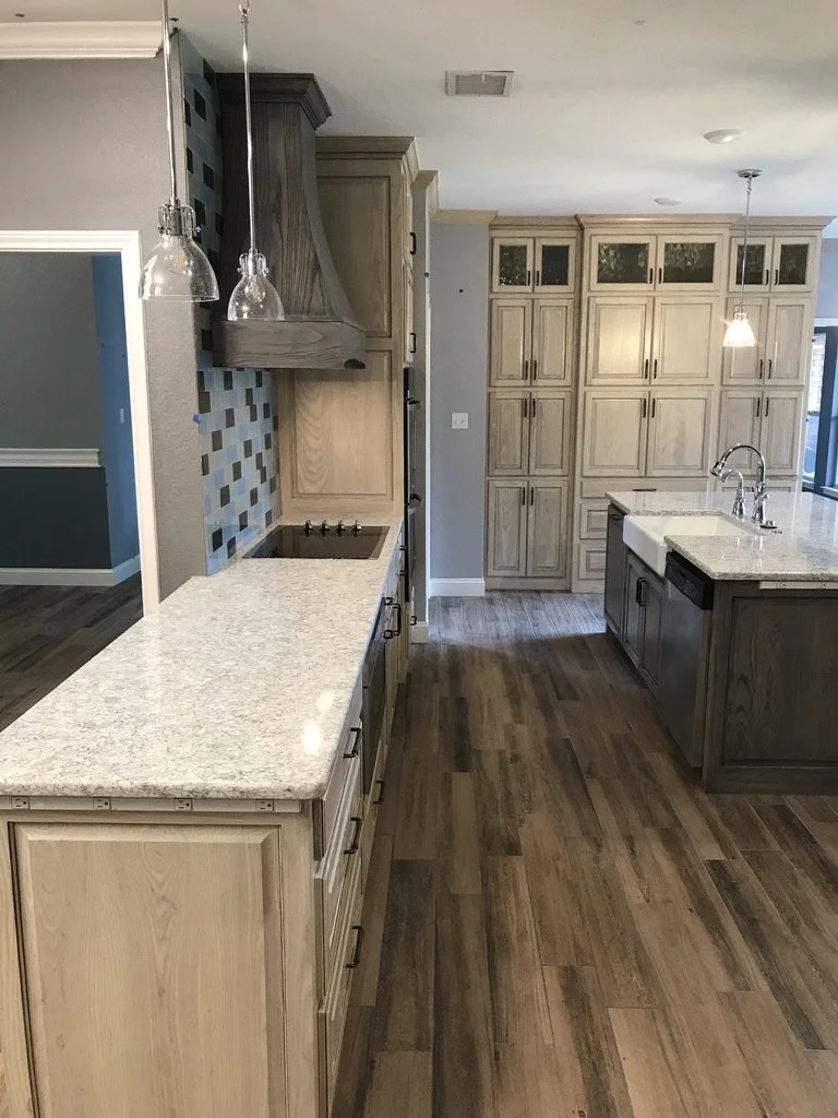 Continuous prep surface meets a statement tile feature and custom hood opposite the island.