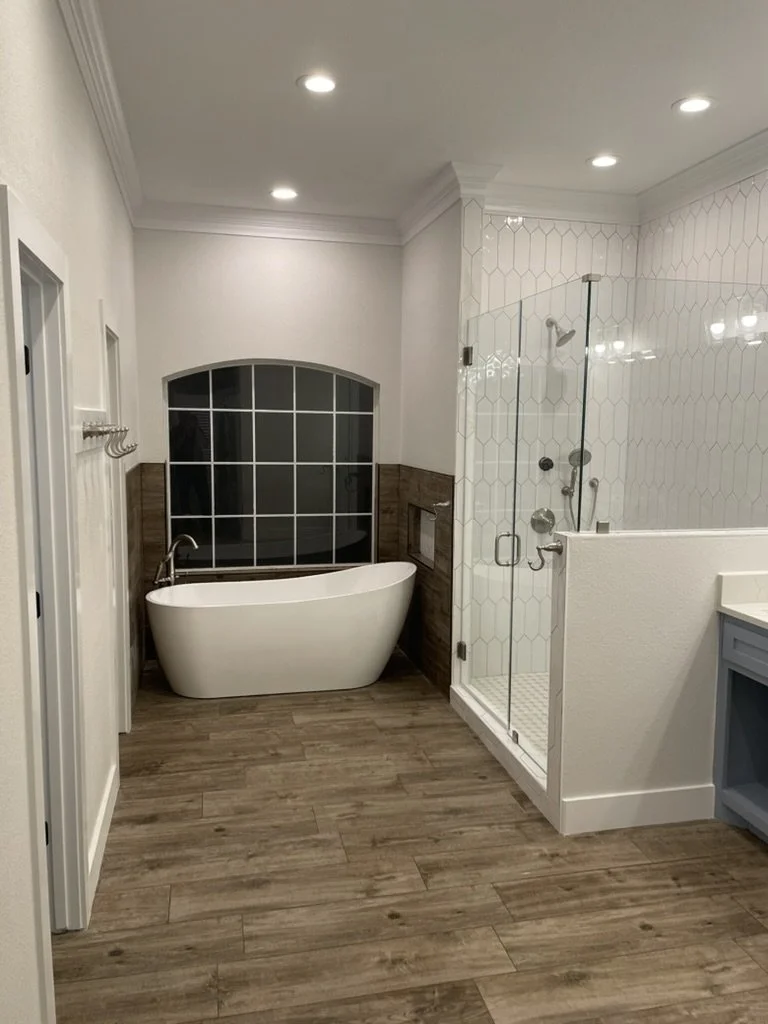Warm wood look flooring and a bright window complement the walk in shower and soaking tub.