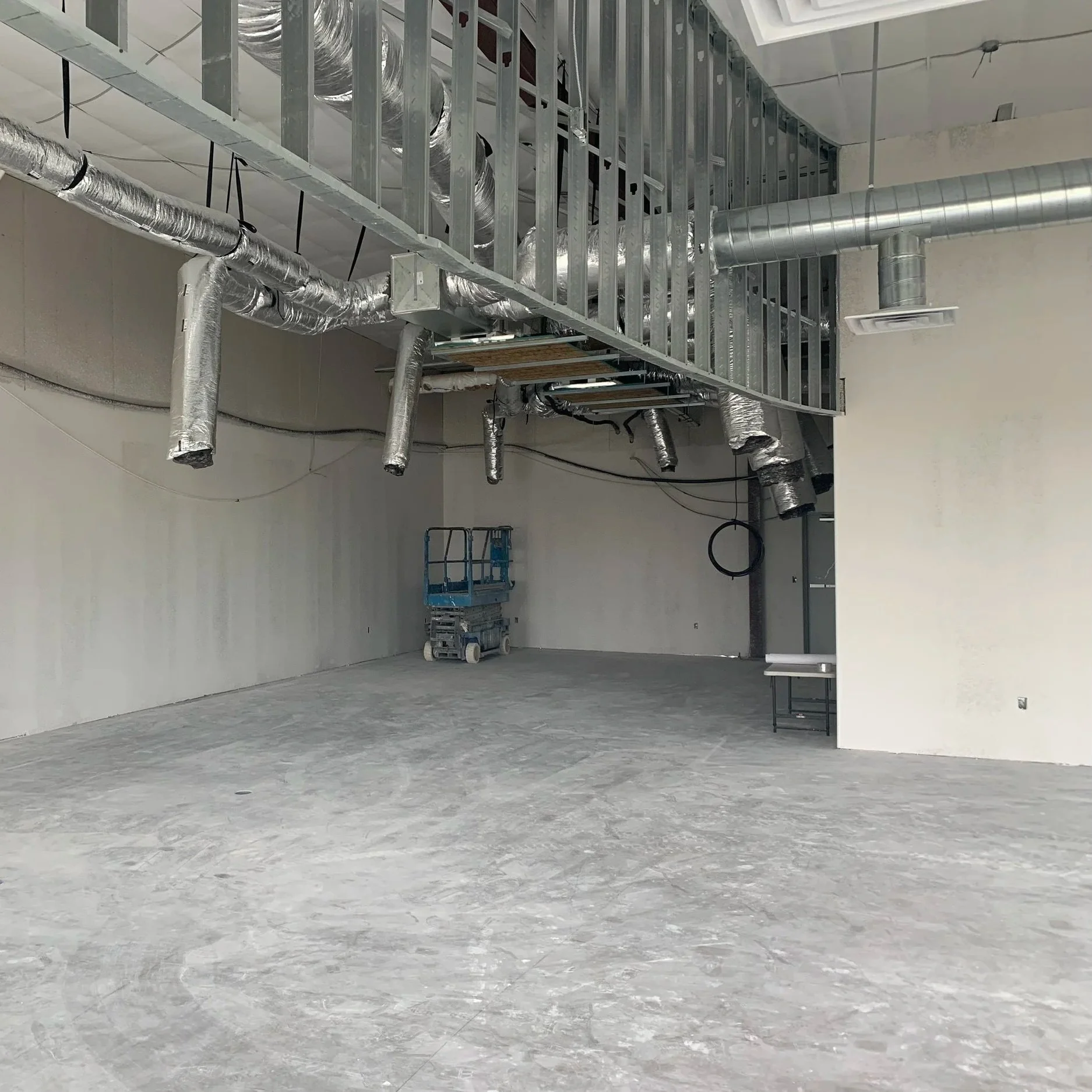 Retail interior under construction with exposed ductwork and metal stud framing.