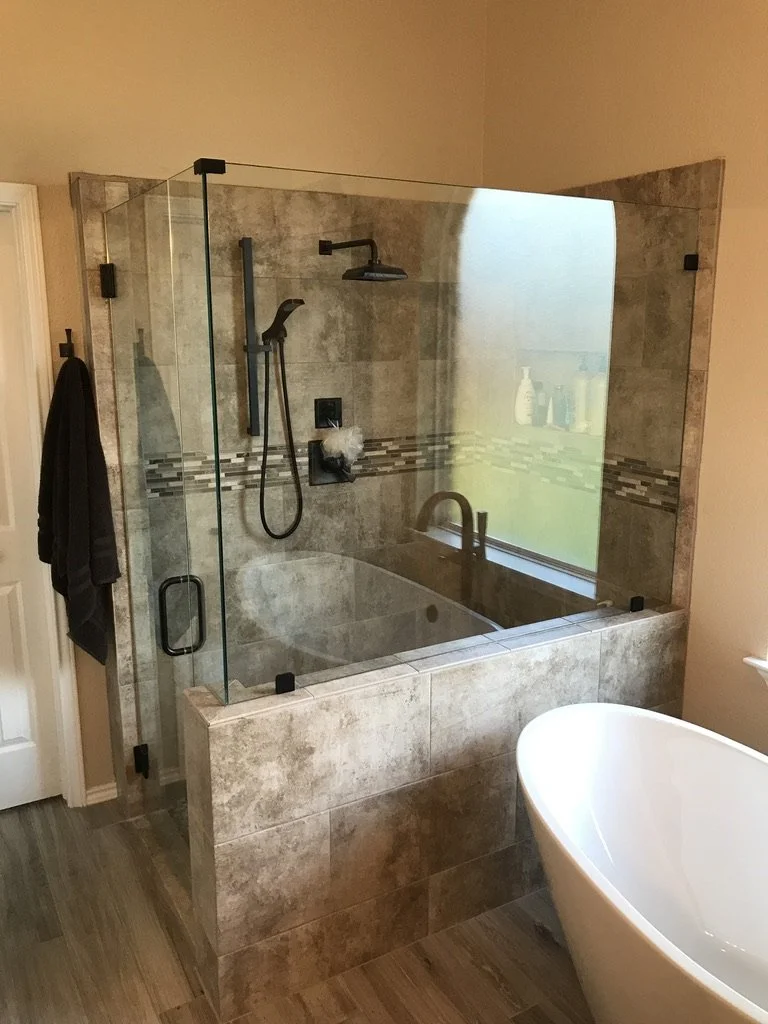 Warm tile and clear glass keep the bath open while adding modern fixtures.