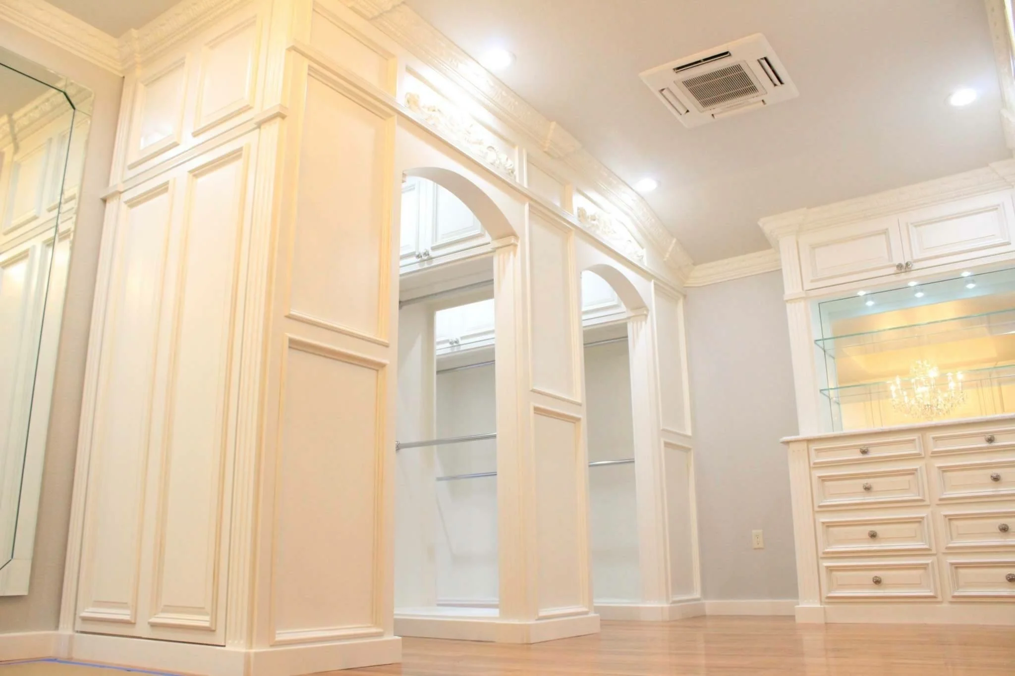 Bespoke closet system with decorative panels, lighting, and integrated circulation.