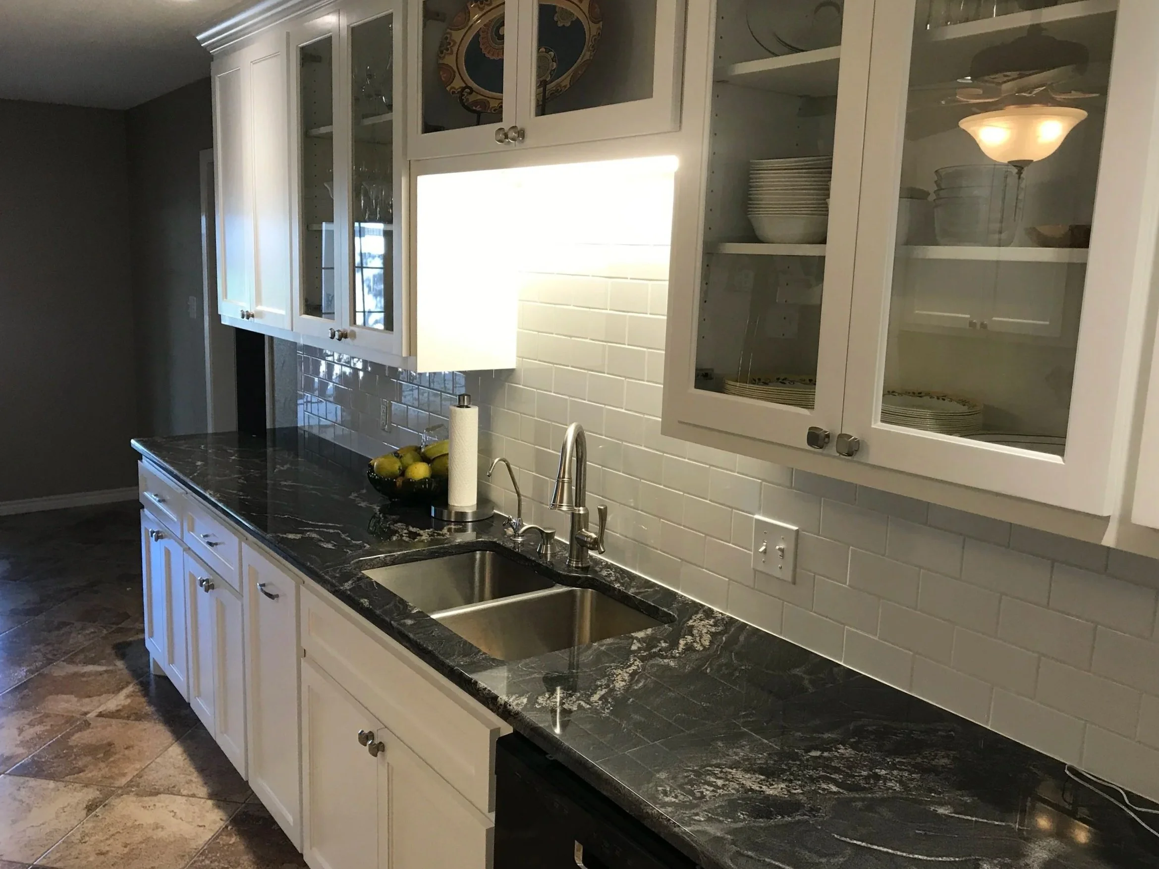 Updated galley wall with quartzite style countertops, glass uppers, and under cabinet lighting.