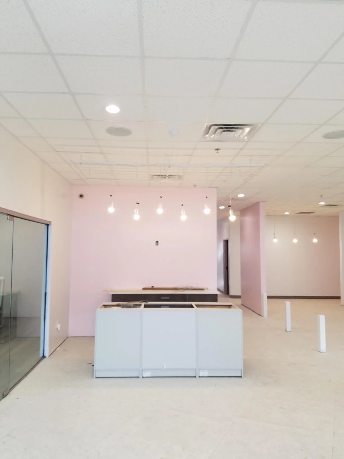 Framing and finishes in progress at reception with pendant lighting and service counters.