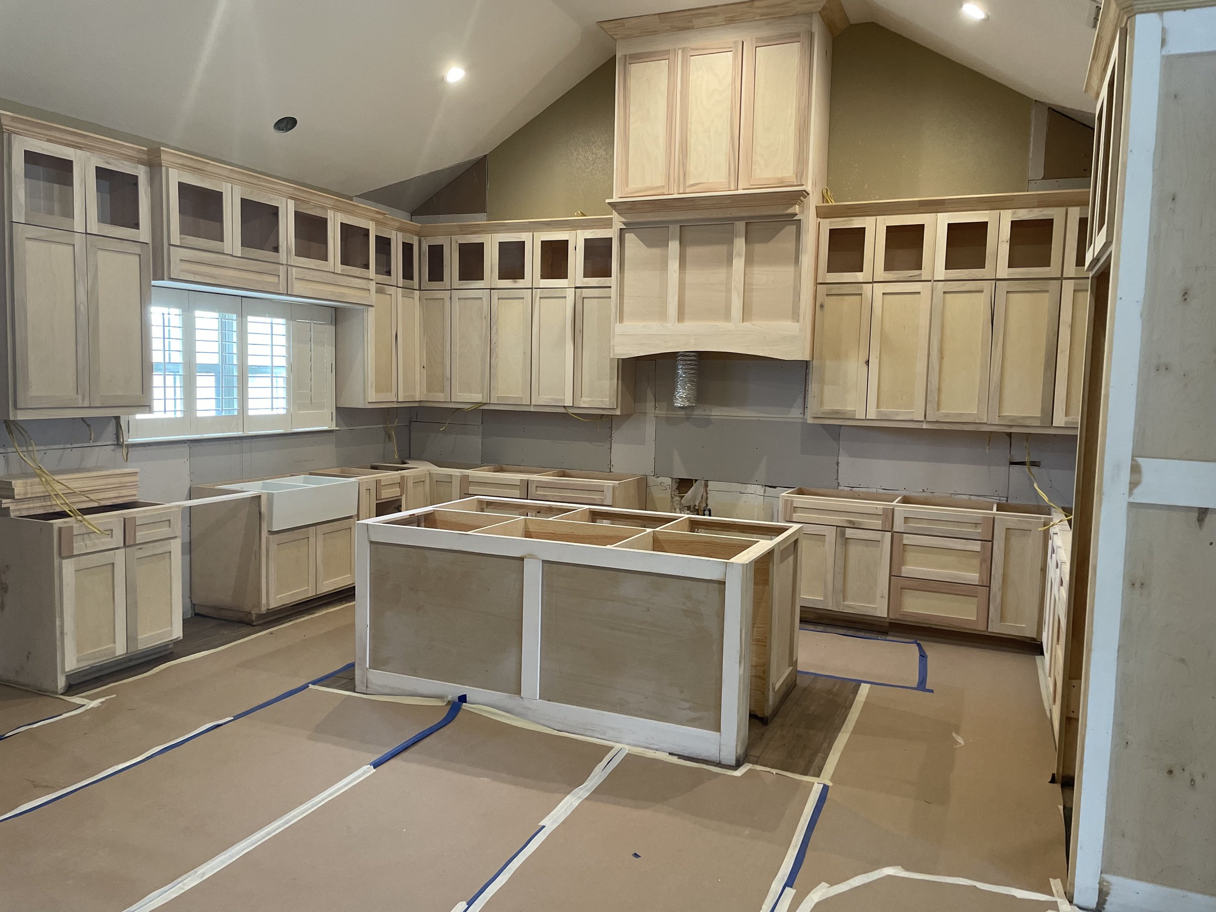 Kitchen under renovation with unfinished custom cabinets and island framing.
