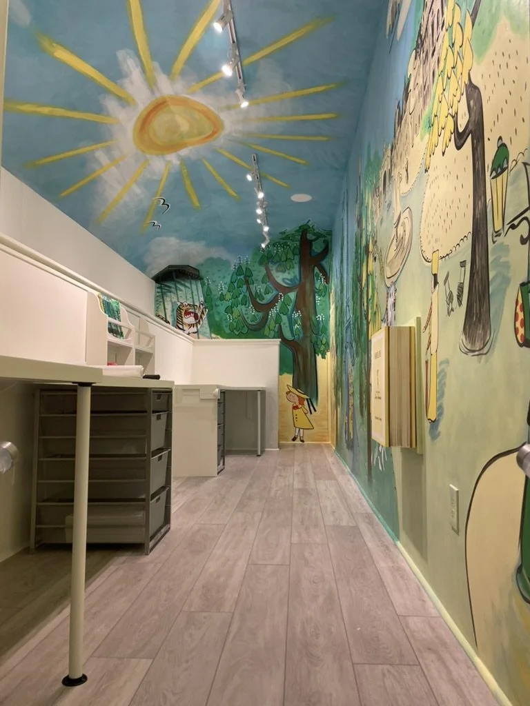Playful mural ceiling and wall with integrated desks and lighting installed during interior buildout.