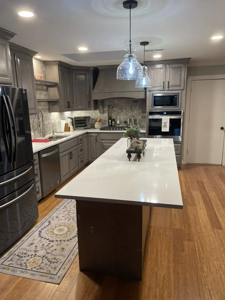 Custom hood and textured stone backsplash frame the cooktop with coordinated hardware and lighting.