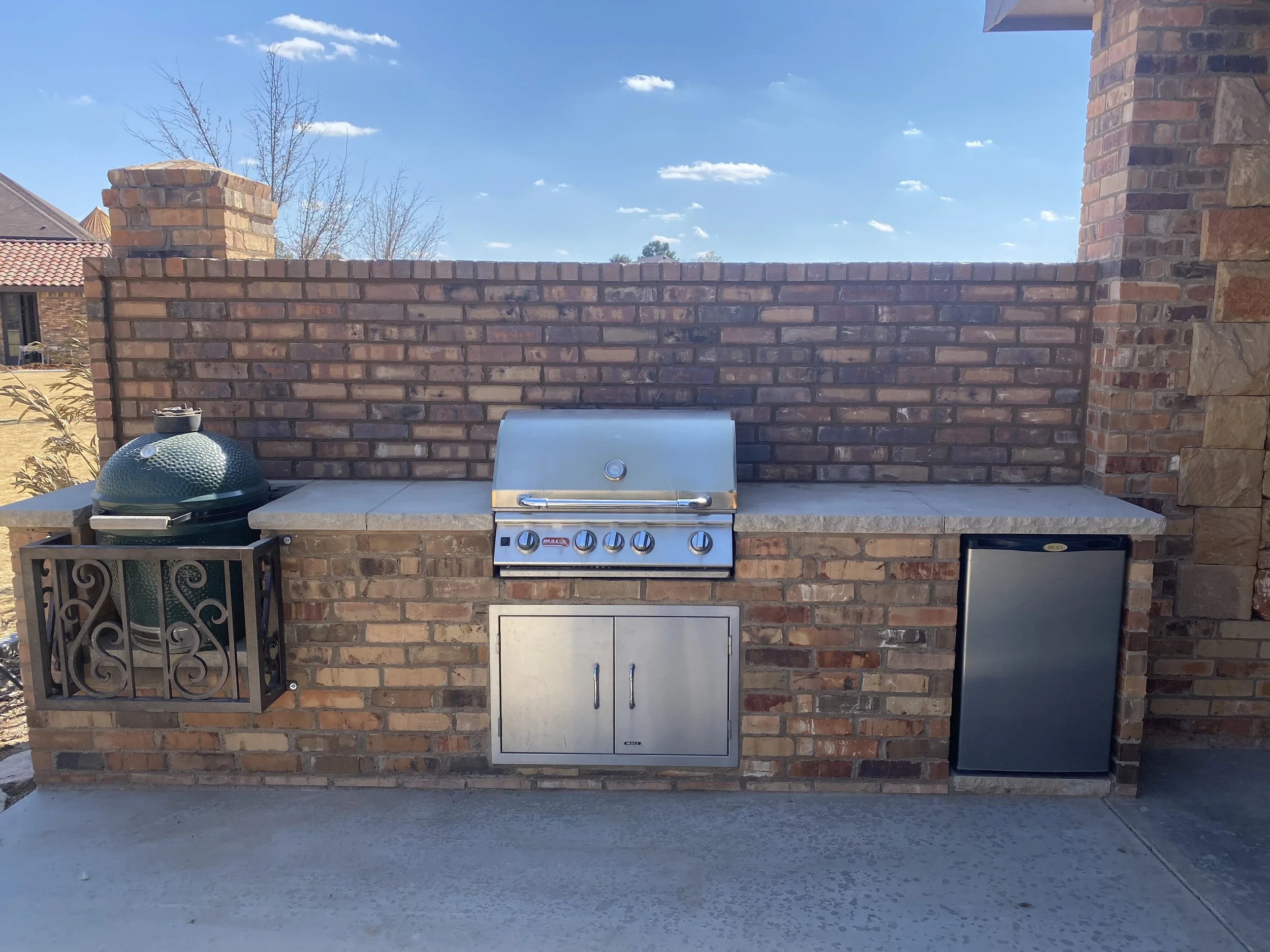Brick outdoor kitchen with grill storage and counter space.