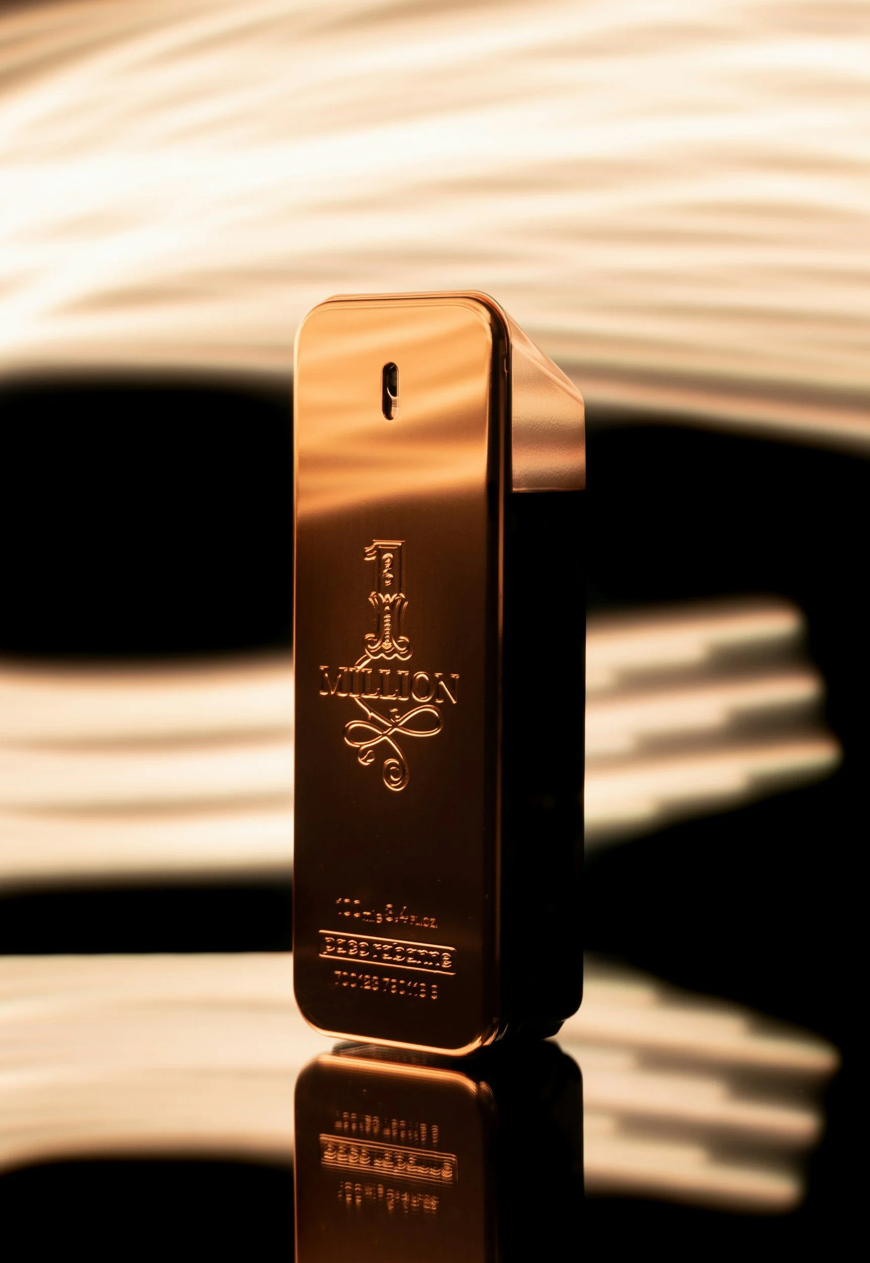 A shiny gold bar with the inscription '1 MILLION' and a weight of 34.1 ounces, placed on a reflective surface with a blurred background of a book and a wave pattern.