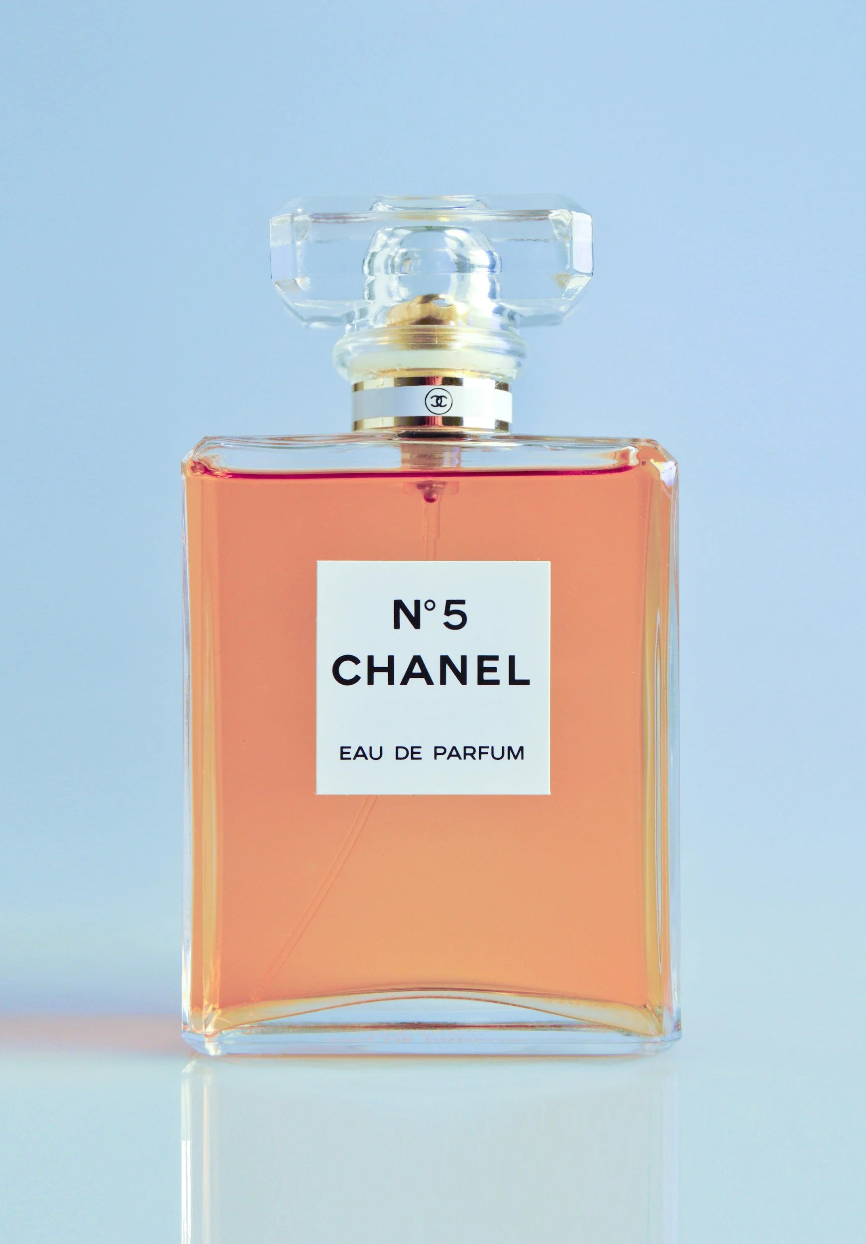 A bottle of Chanel No. 5 perfume with pink liquid, rectangular glass design, and a clear decorative cap