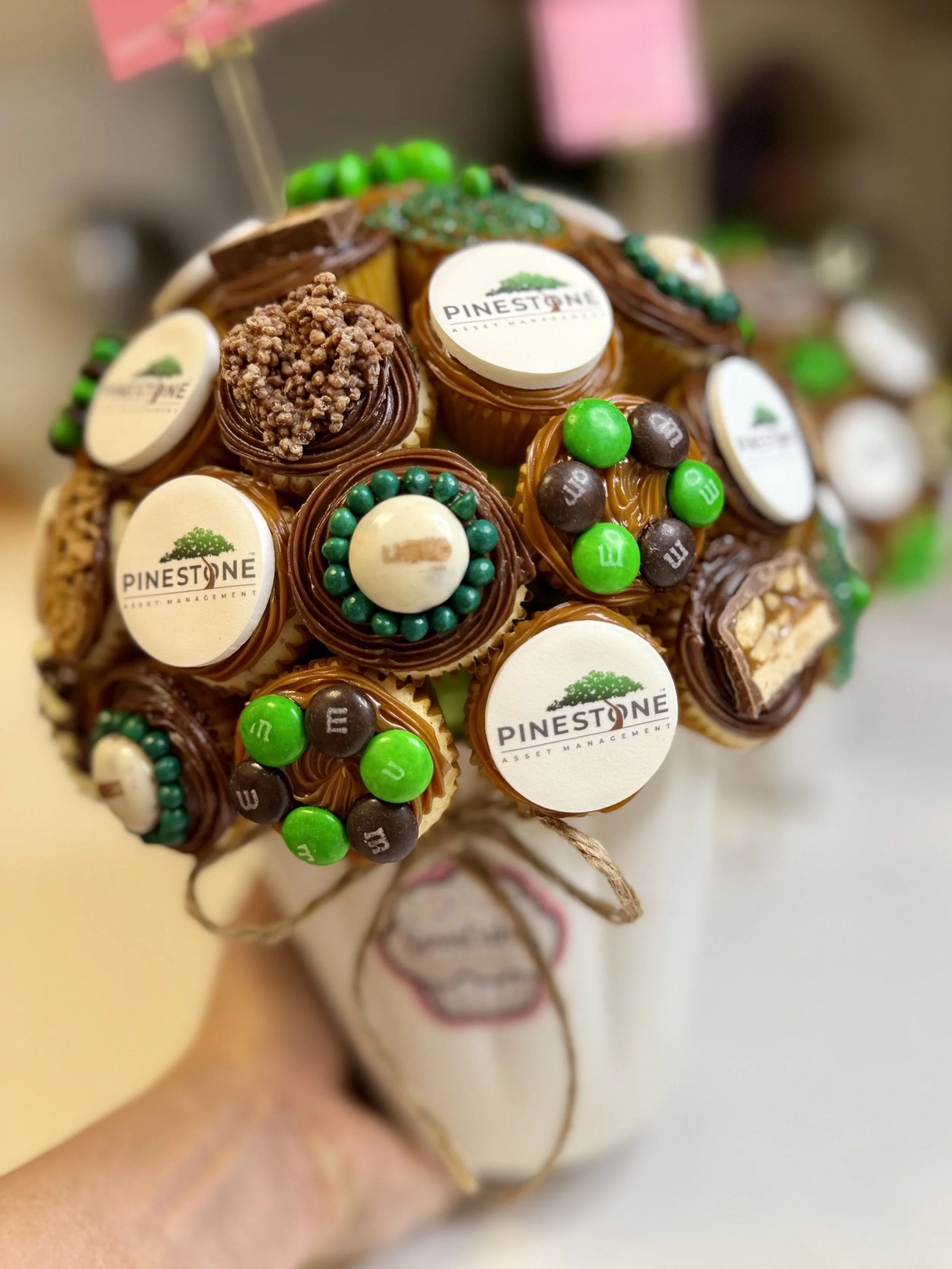 Custom mini cupcake bouquet with chocolate frosting and branded decorations for a corporate event