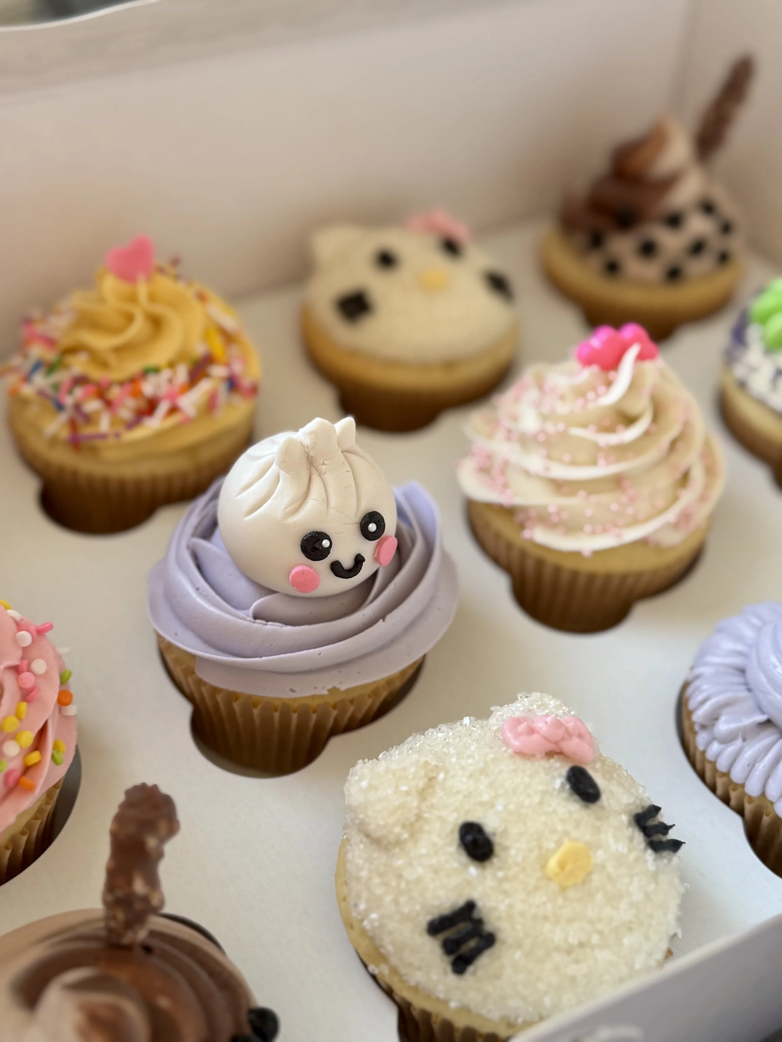 Twelve cupcakes with kawaii themed decorations in soft pastel colours