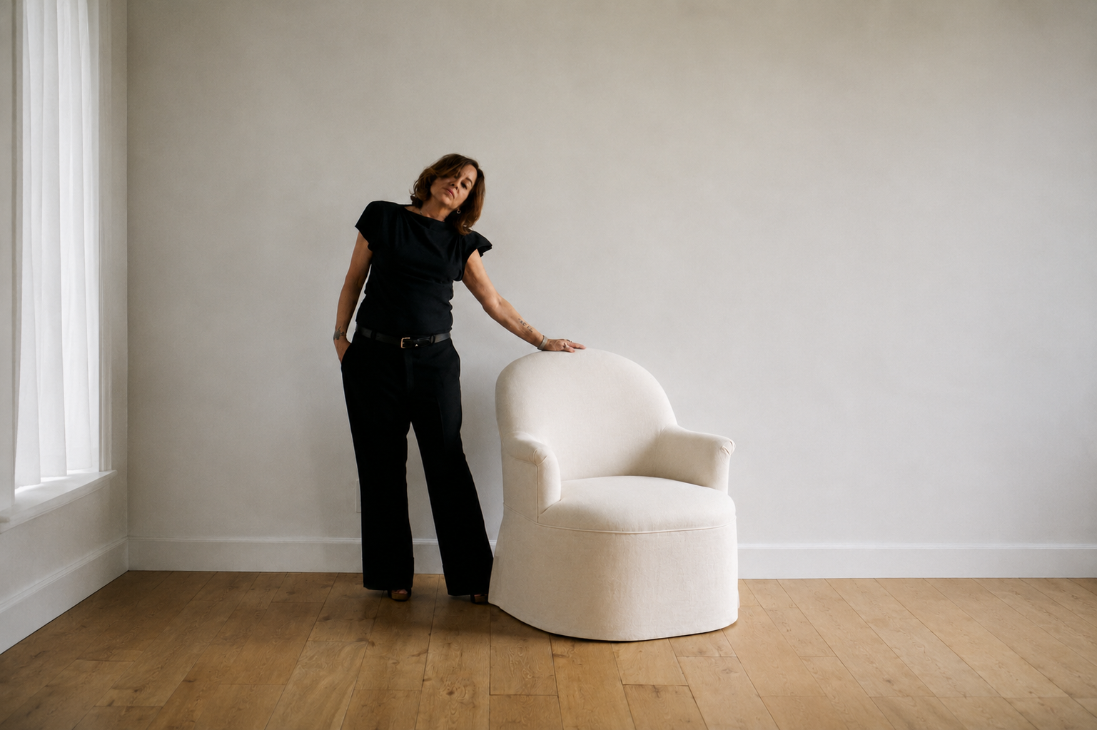 Cream-colored fabric draped over chair and hanging to floor in front of plain gray wall.