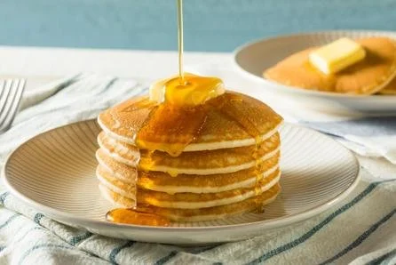 Stack of pancakes with butter and syrup on a plate