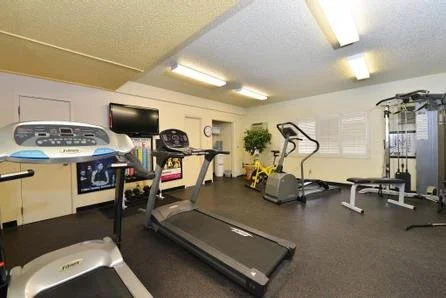 Gym room with treadmills, elliptical machines, and exercise equipment.