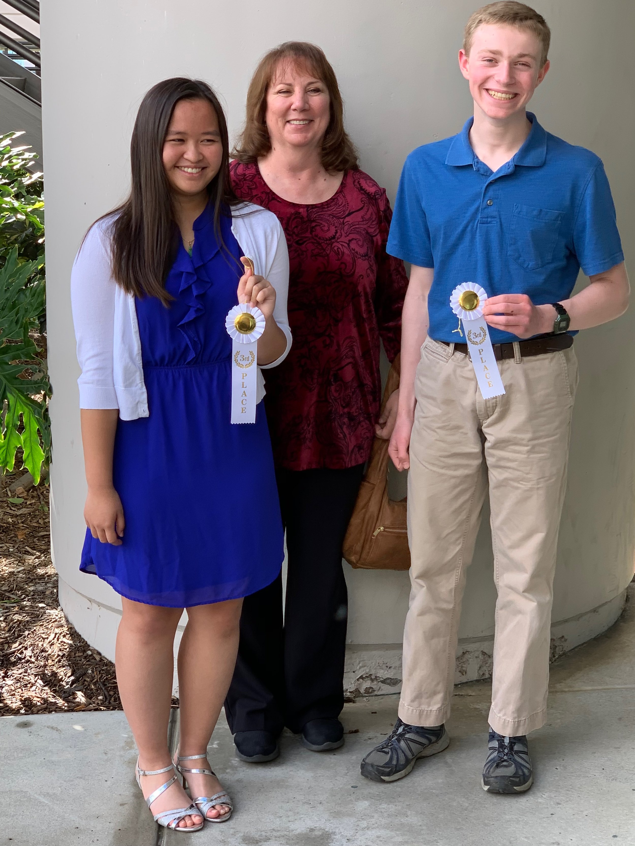 Advanced piano students after a recital performance, holding awards