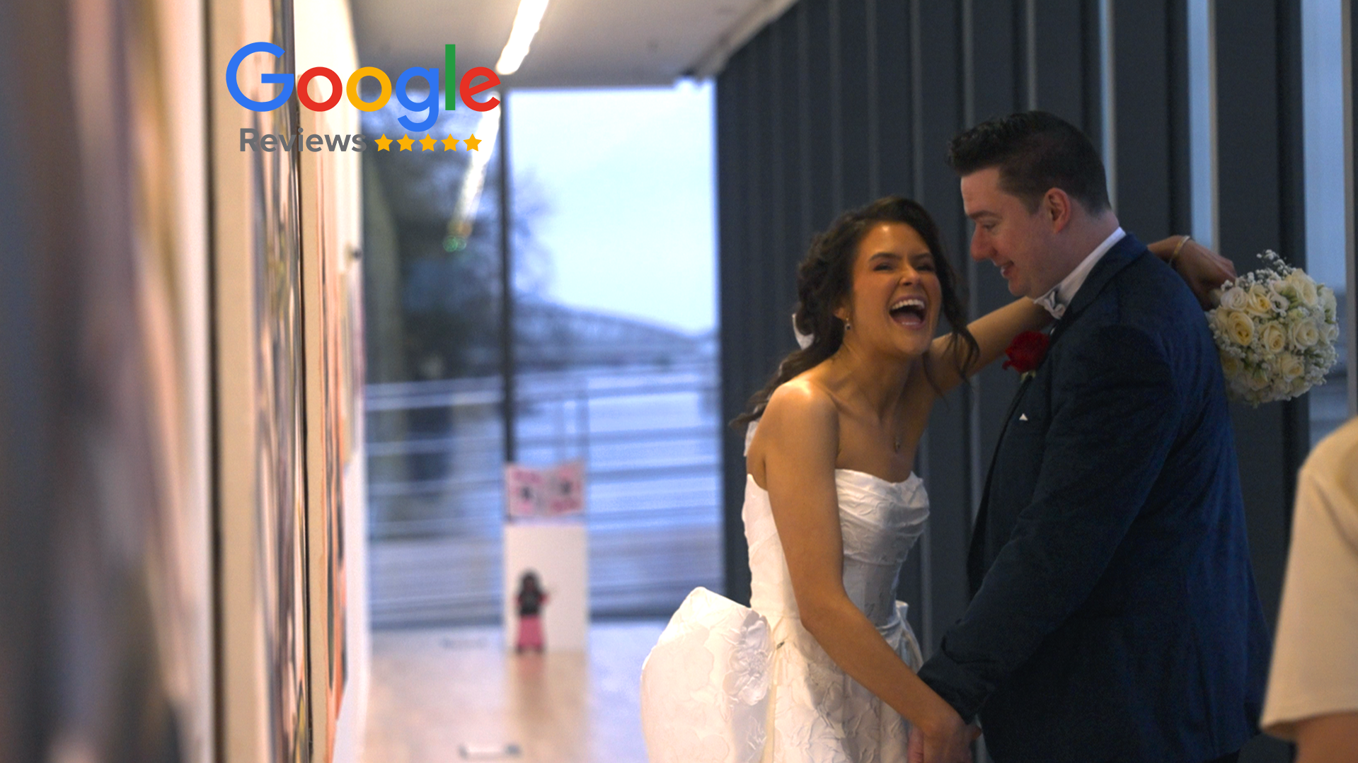 A happy bride and groom share a kiss at their wedding reception in a modern venue, with bridesmaids and a groomsman nearby.