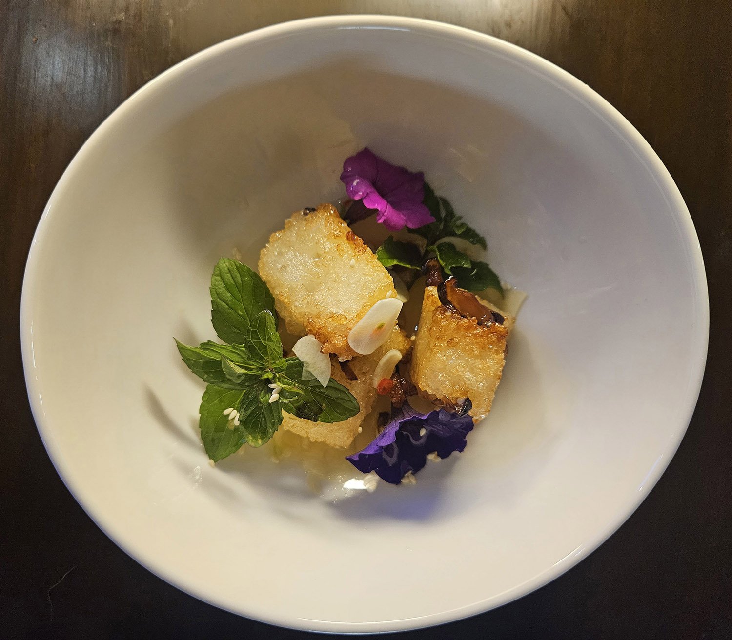 Fried cheese cubes garnished with mint and edible purple and green flowers