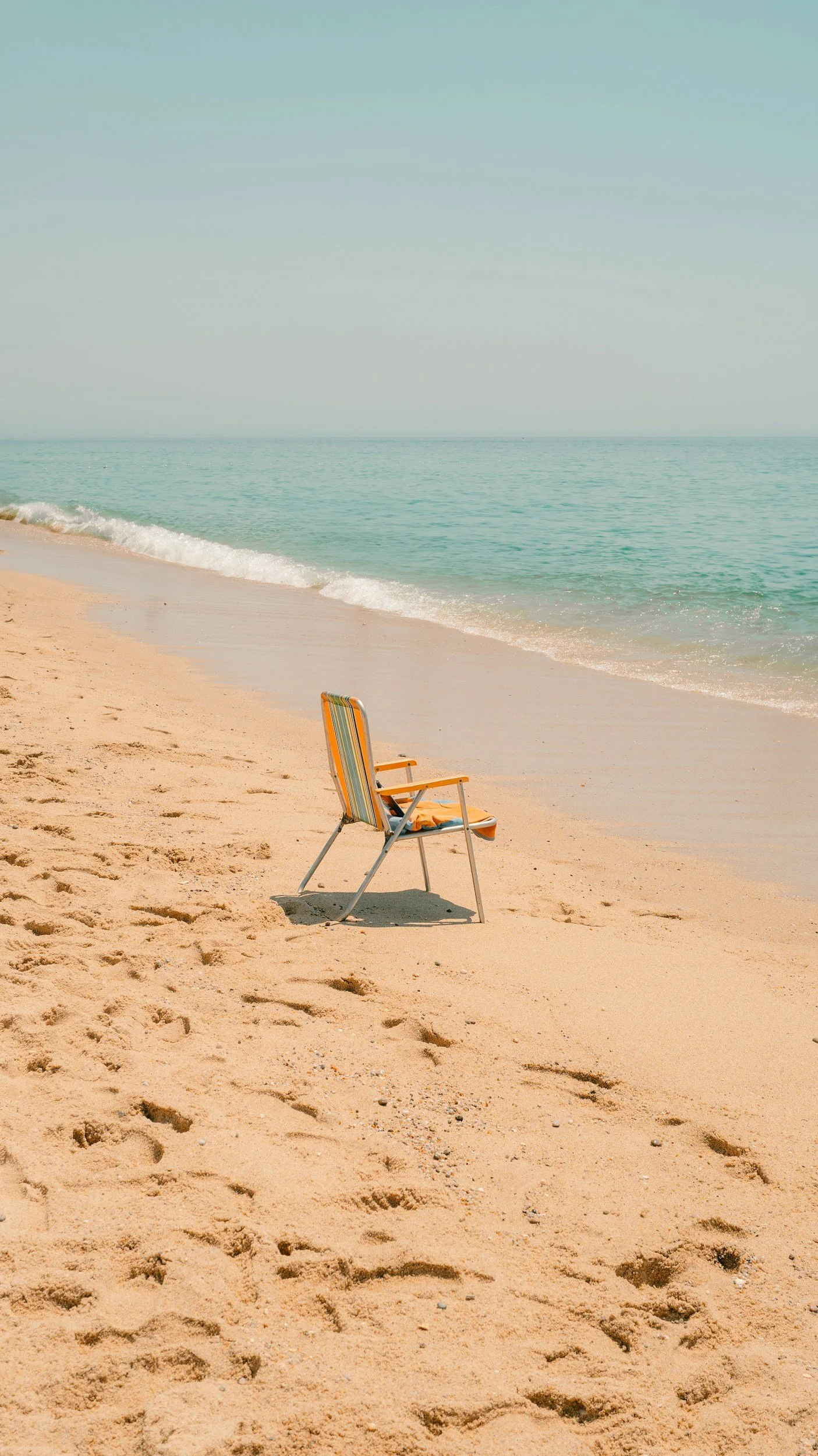 Single beach chair representing the contrast of summer grief in Denver