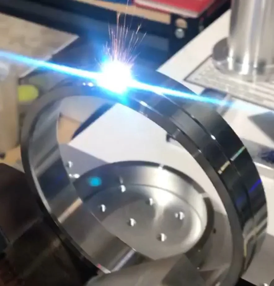 Close-up of a metal ring being welded, with sparks and bright light at the weld point.
