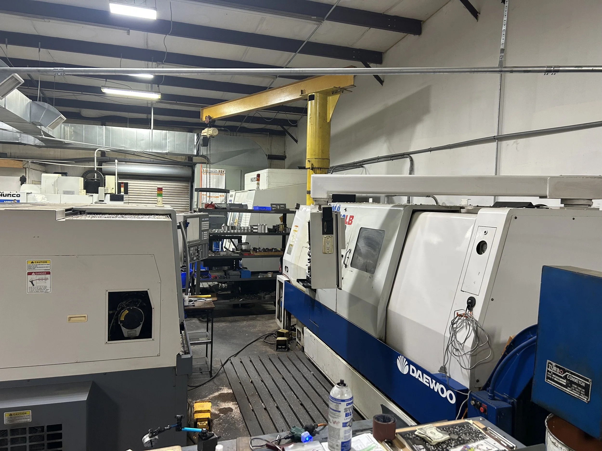 Industrial workshop with multiple CNC machines, tools, and equipment, including a Daewoo CNC machine and workbenches.