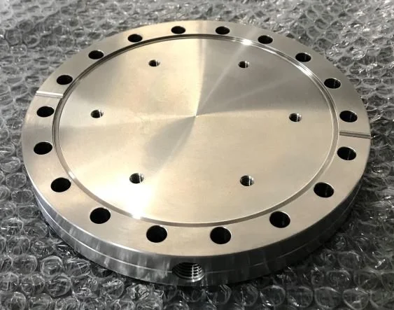 A shiny, circular metallic component with multiple evenly spaced holes around its perimeter, placed on bubble wrap.