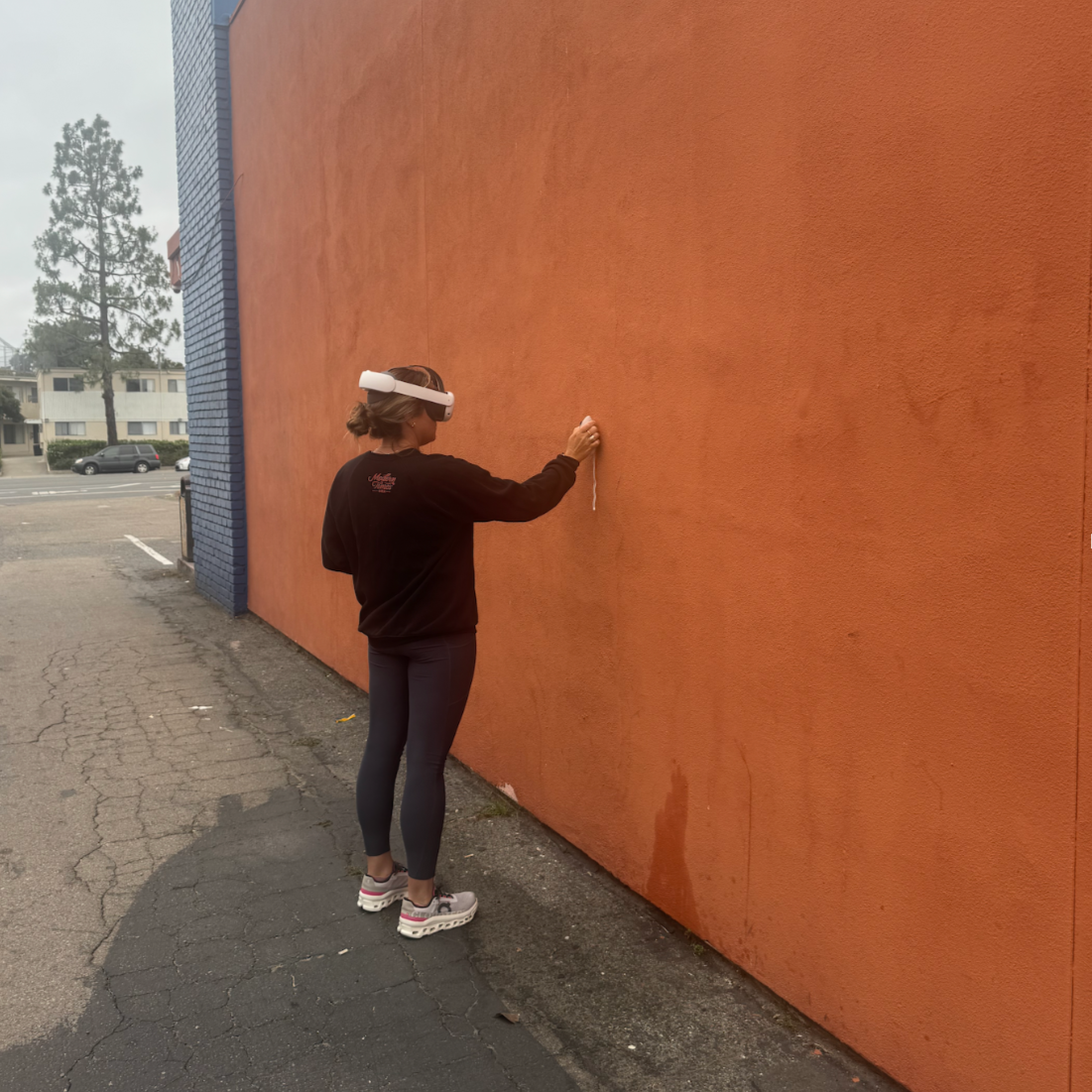 Artist showcasing VR headset on a big tan wall.