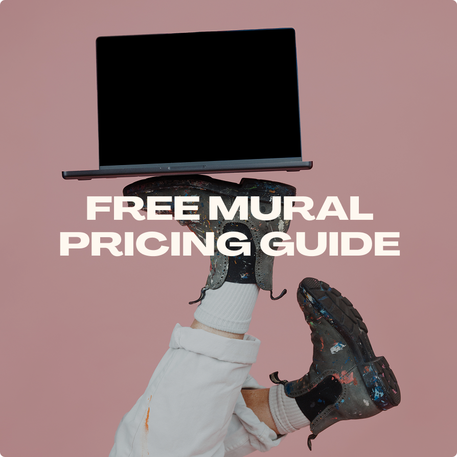 A person holding a laptop upright above their head with one hand, wearing painting gloves and boots, against a pink background, with the text 'FREE MURAL PRICING GUIDE' overlaid.