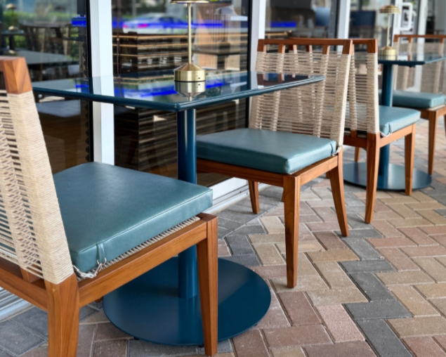 Outdoor restaurant seating with wicker and wood chairs around a glass-topped table