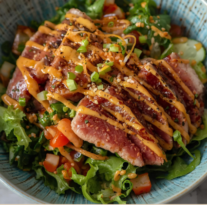Seared tuna steak on a bed of mixed greens and chopped vegetables, drizzled with a spicy mayo sauce and garnished with chopped green onions.