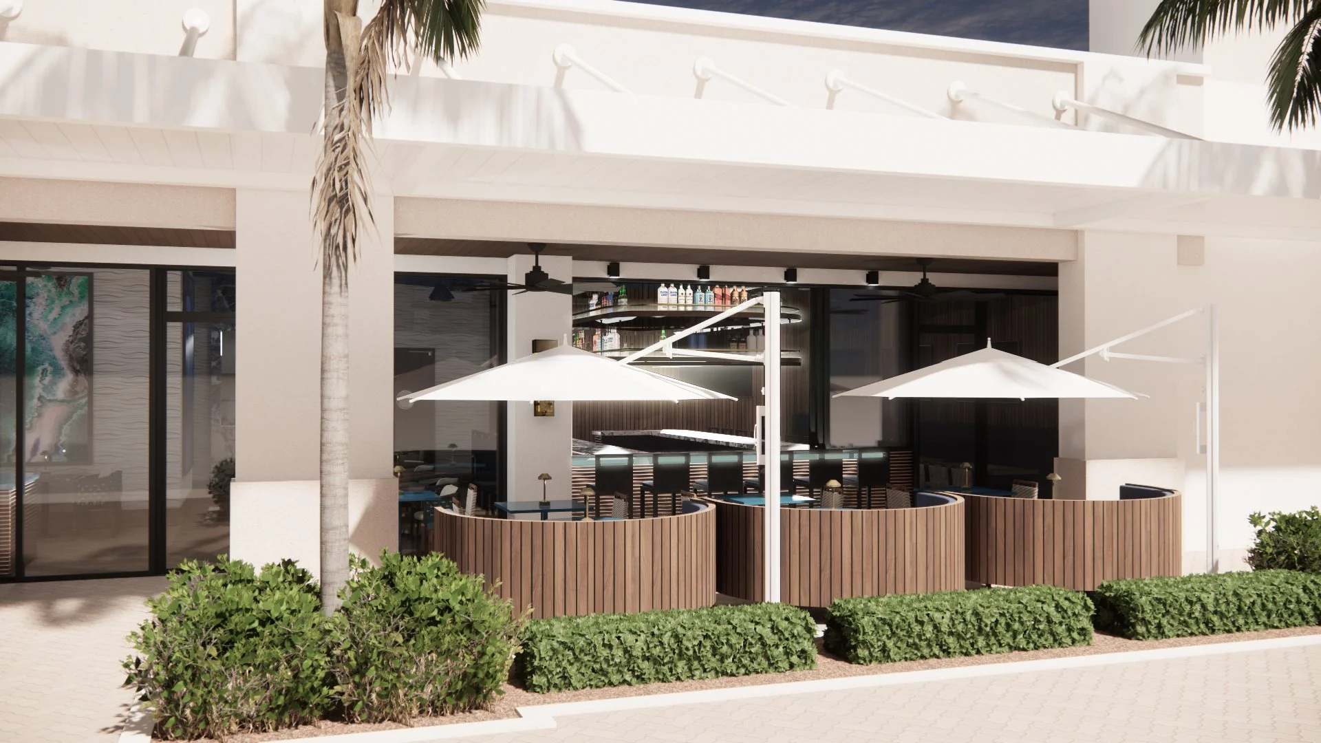 Outdoor seating area with white umbrellas, wooden planters, and lush green bushes in front of a modern building with a bar inside visible through glass doors.