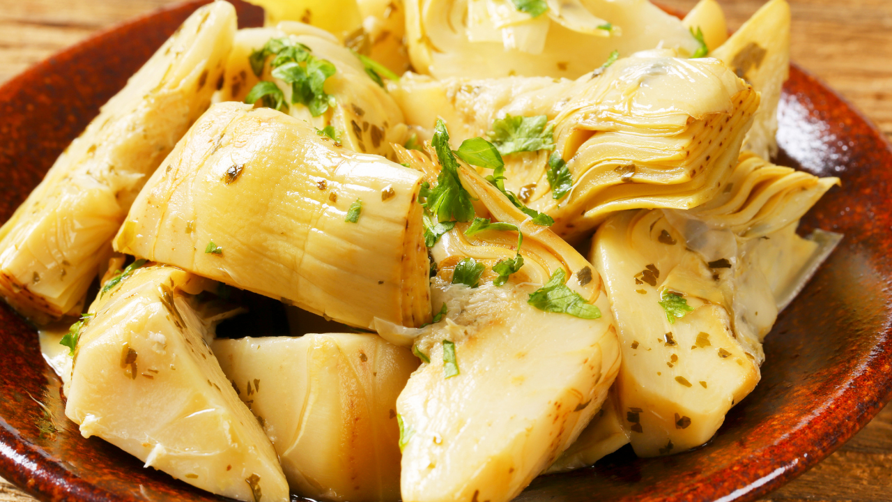 Artichoke hearts garnished with chopped herbs on a ceramic plate.