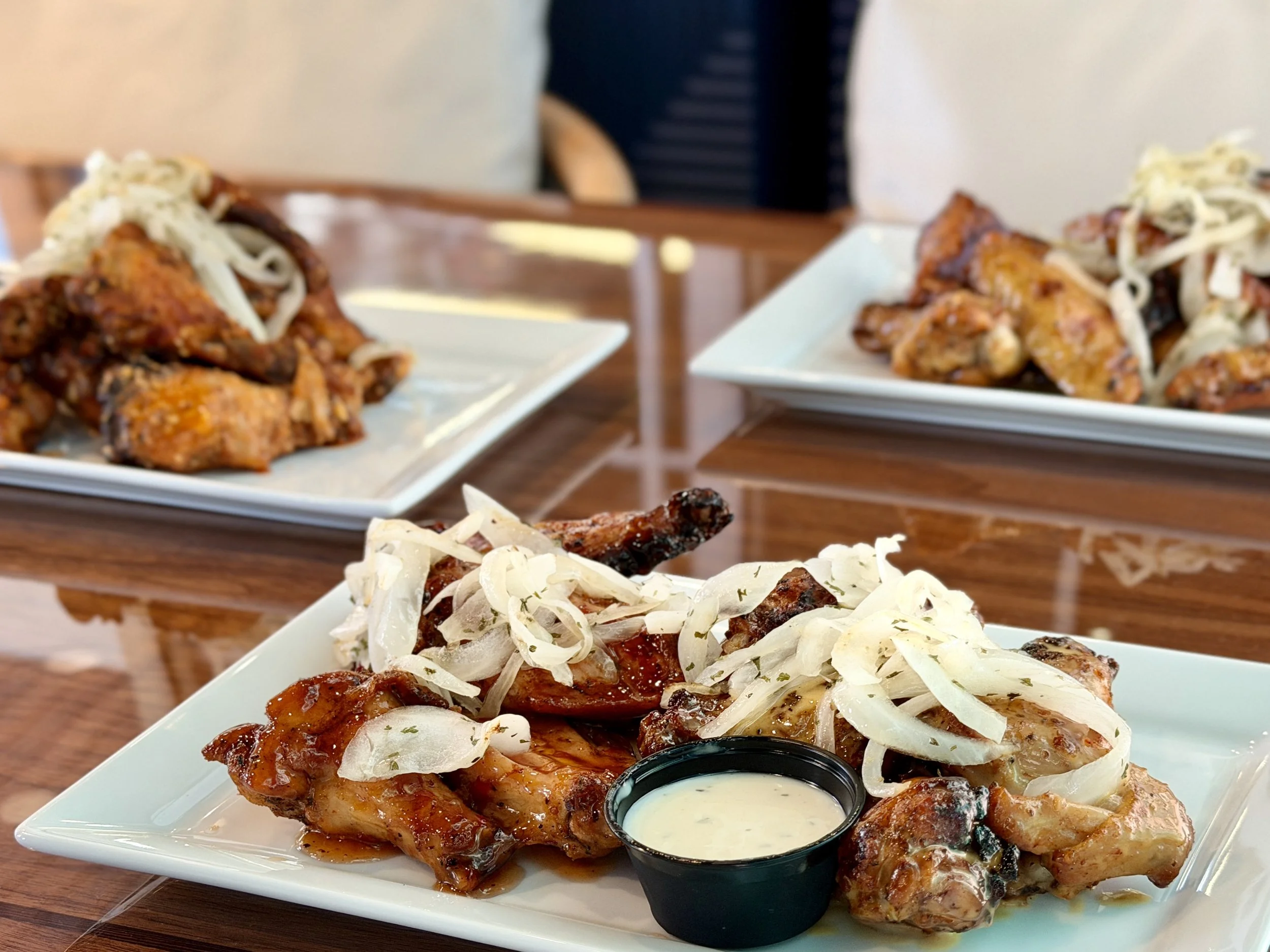 Plate with barbeque ribs topped with shredded cheese, fries, and a side of dipping sauce on a white plate.