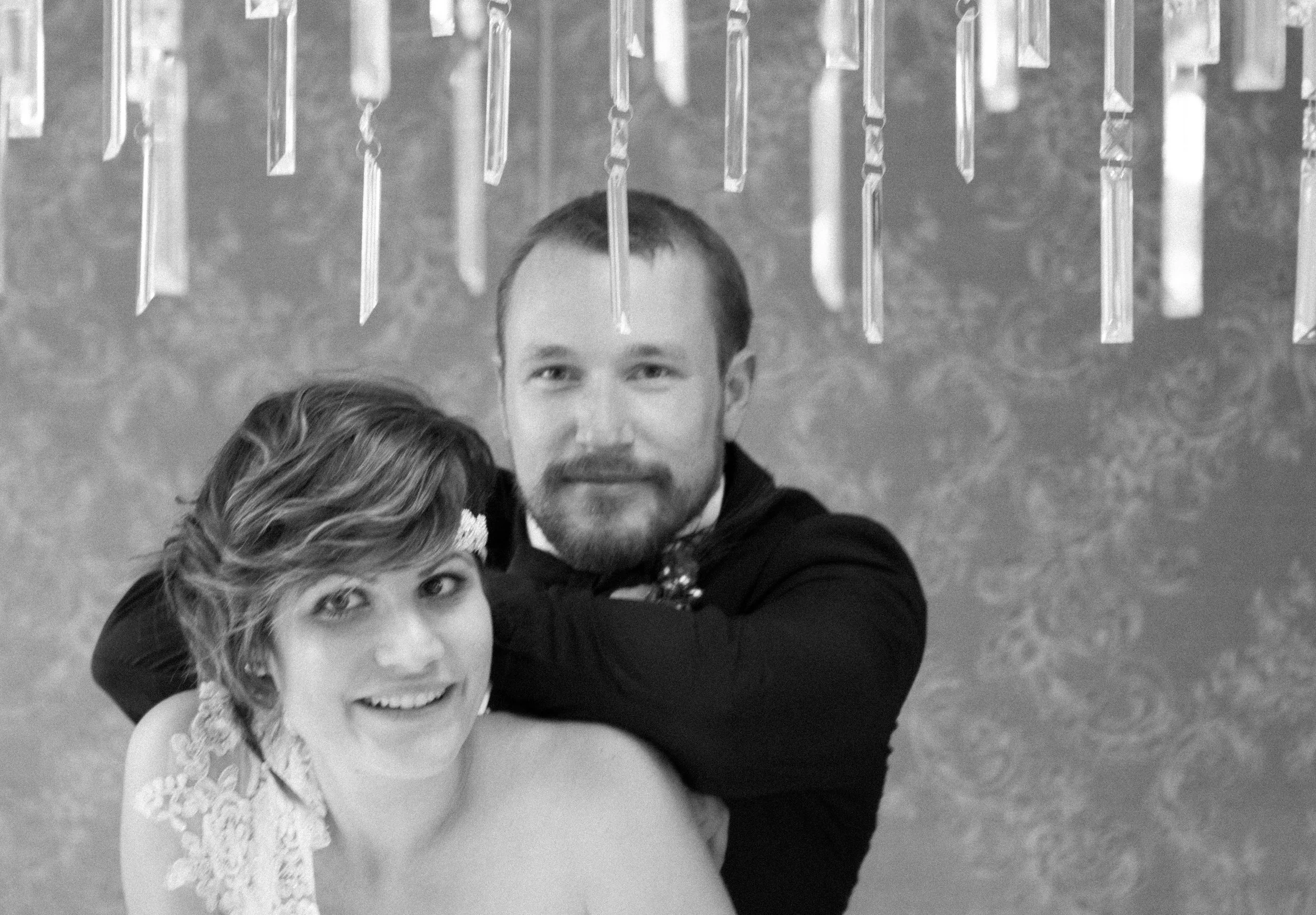 Ein Mann und eine Frau, die sich umarmen, vor einem Hintergrund mit hängenden Kristallen, Schwarz-Weiß-Foto.