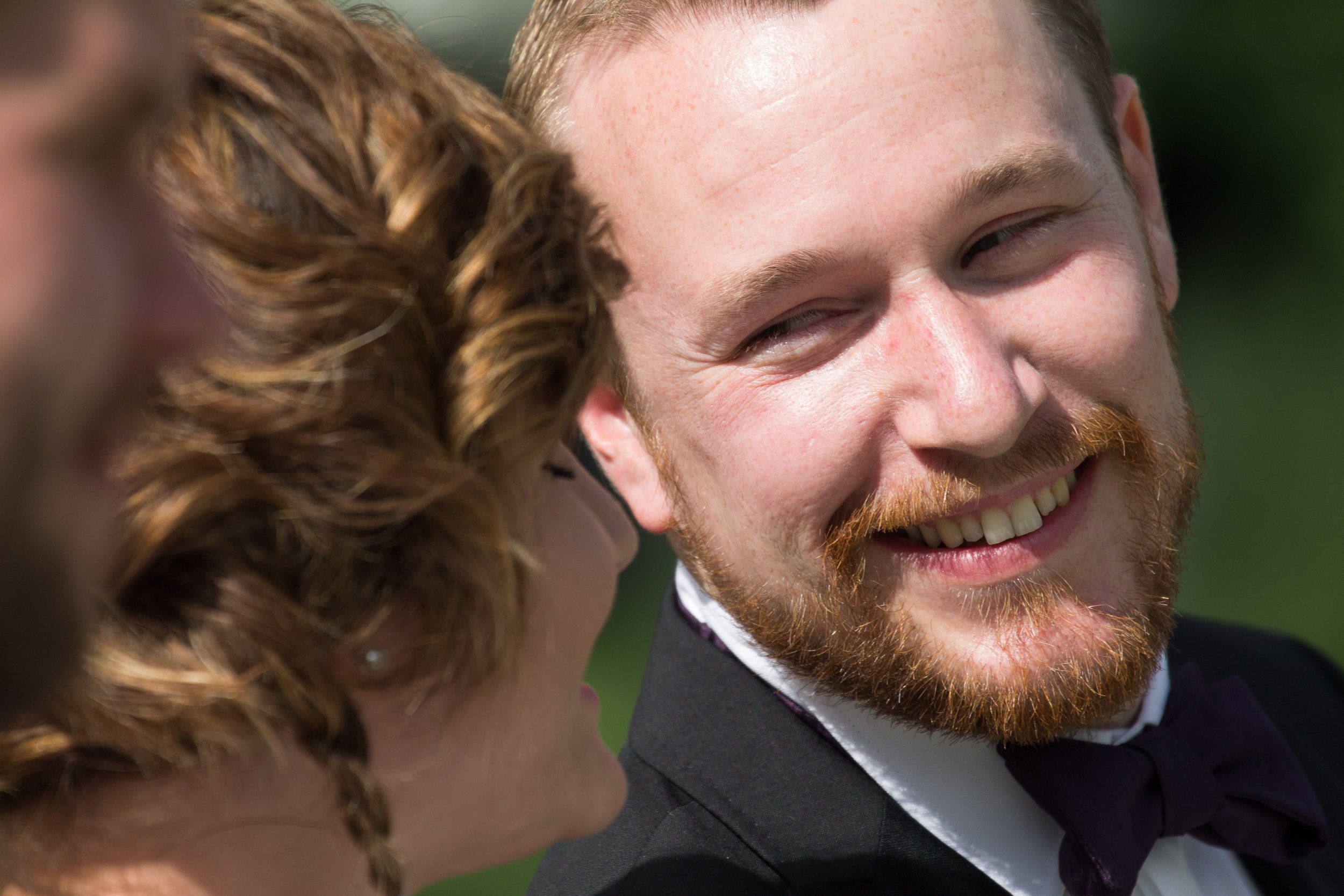 Ein glückliches Paar bei einer Hochzeit, lachend und in einem Gespräch, im Freien bei Tageslicht.