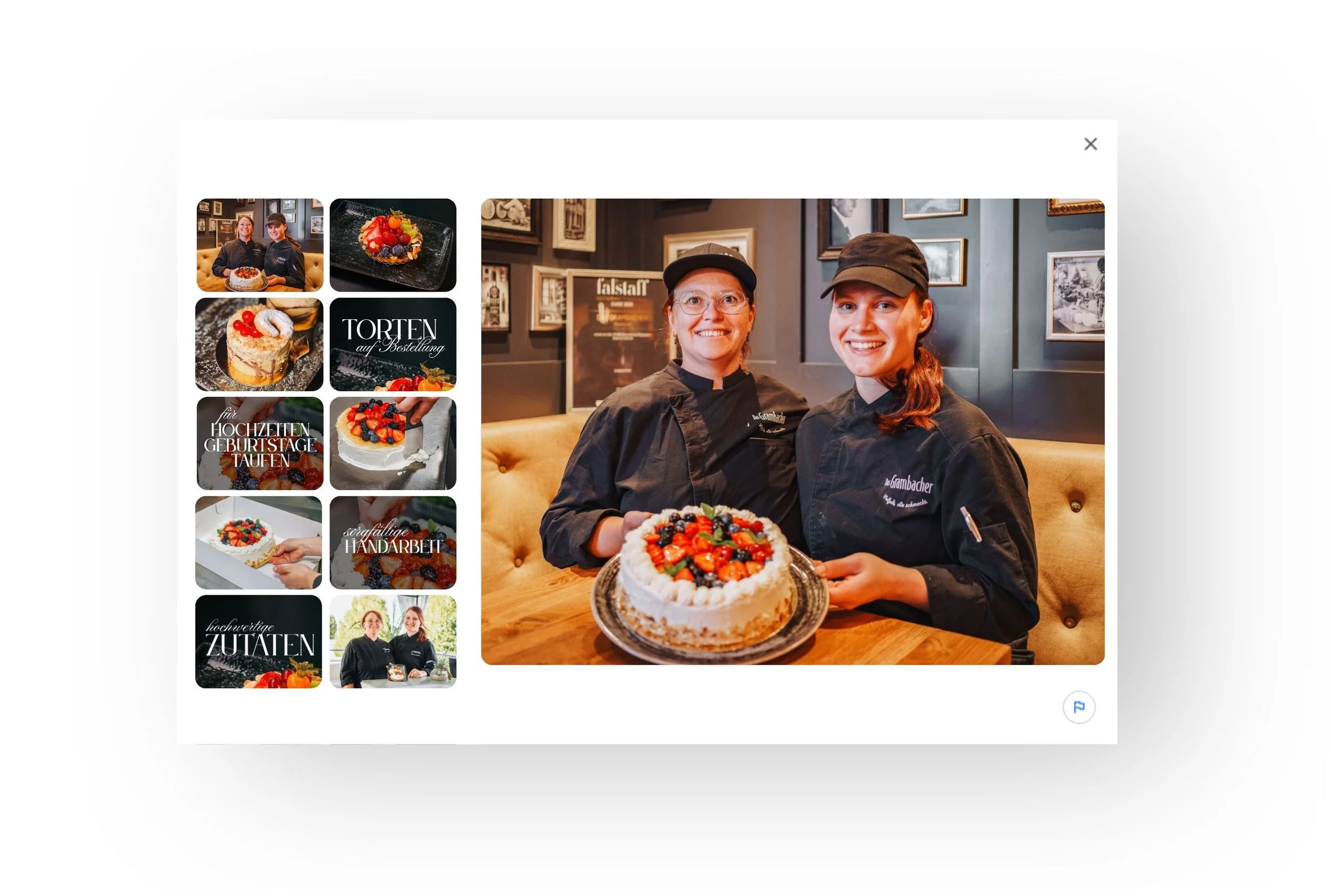 Zwei Köchinnen in schwarzen Uniformen und Mützen präsentieren eine Torte mit Beeren und weißen Verzierung. Die Szenerie befindet sich in einer einladenden, versierten Pâtisserie mit dunklen Wänden und Bildern an der Wand.