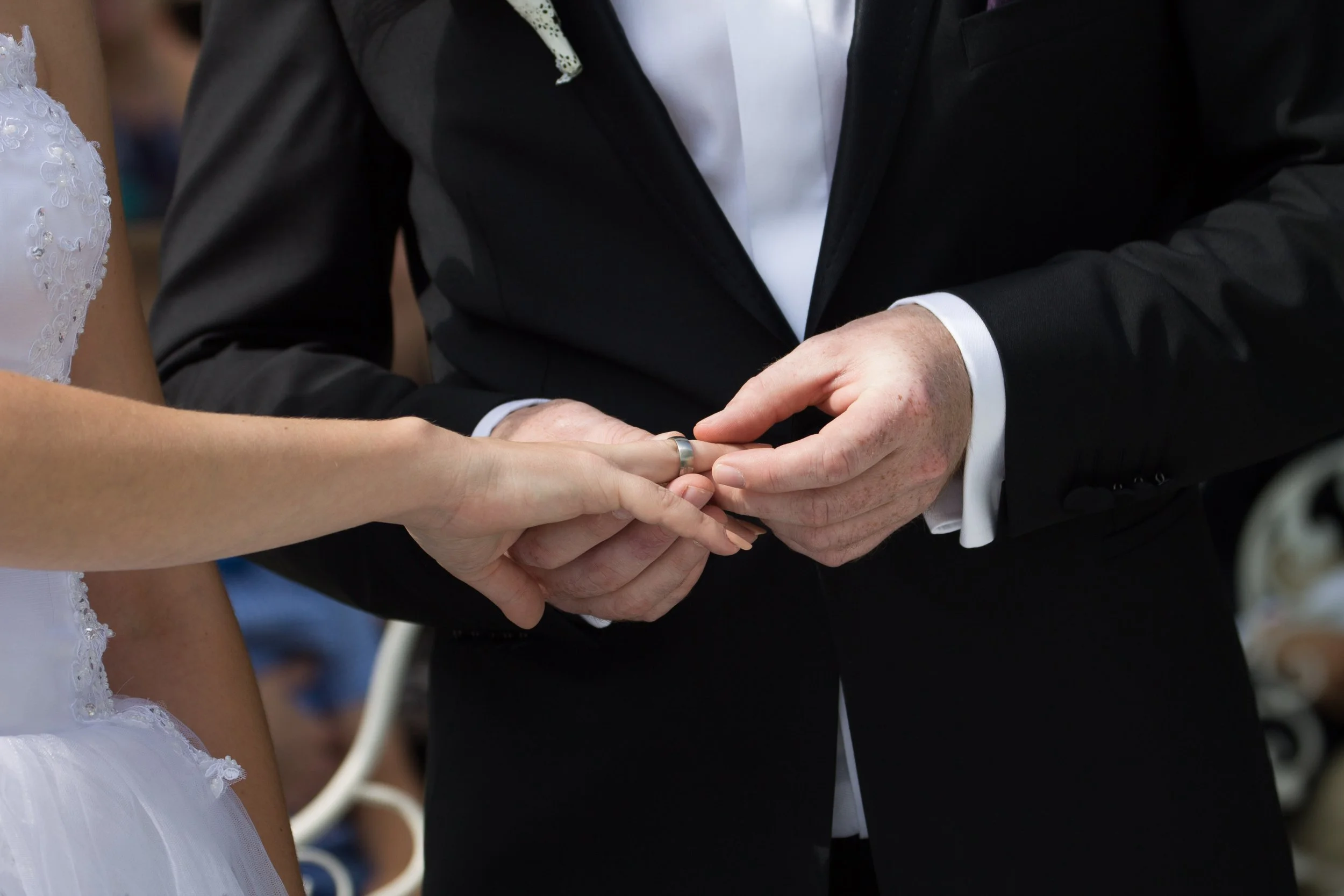 Ein Mann und eine Frau bei einer Hochzeitszeremonie tauschen Ringe, Nahaufnahme von ihren Händen und den Händen