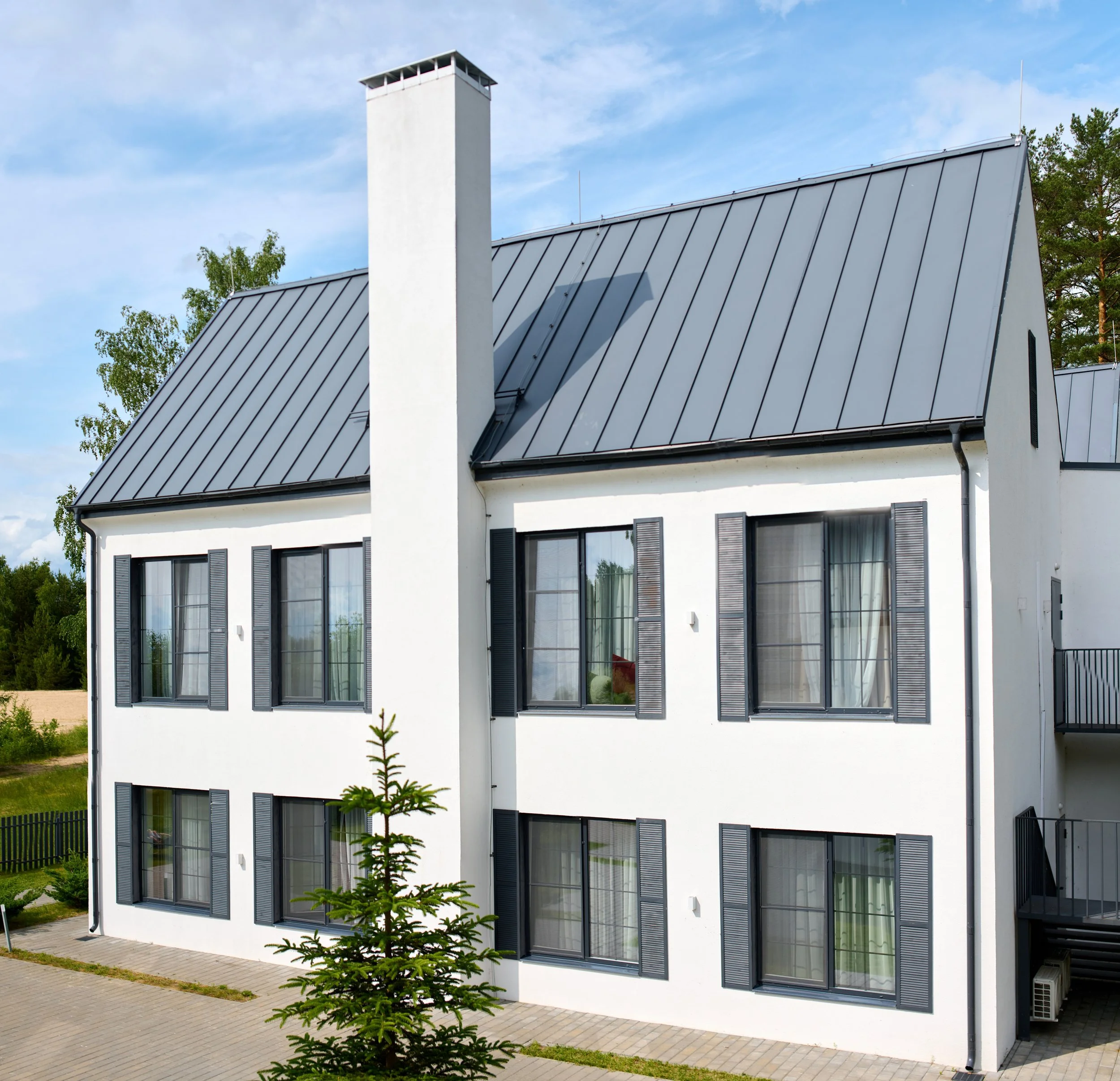 modern white house with metal roof in suburban setting