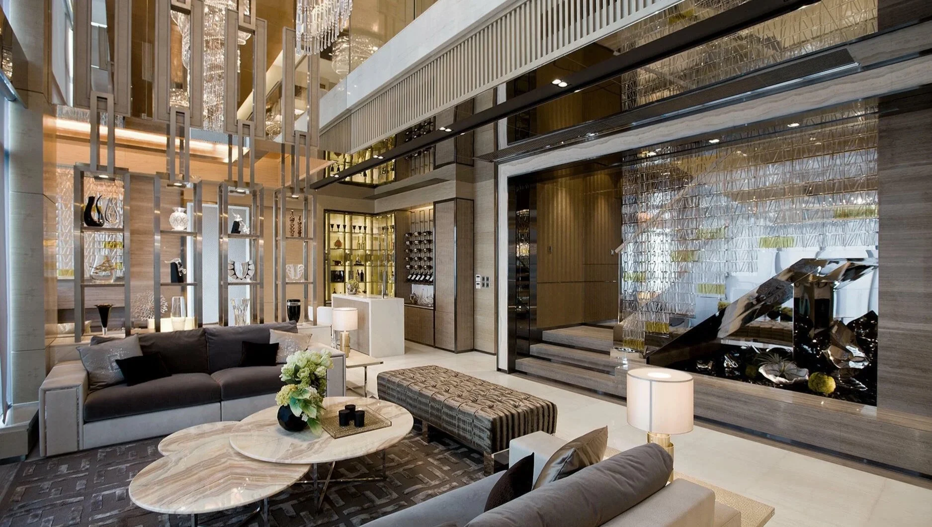 Luxurious residence with modern decor, including a seating area with sofas and armchairs, a marble coffee table with flowers, decorative lamps, glass shelves with art pieces, and a large metallic sculpture in a nook.