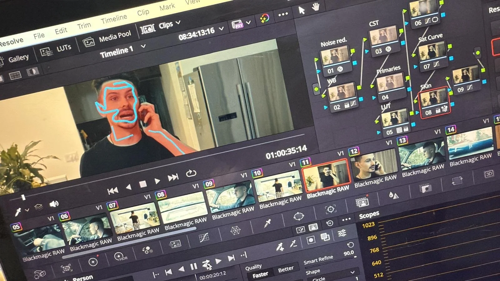 A computer screen displaying video editing software with a timeline of video clips, showing a scene where a person in a dark shirt talks on the phone with digital outlines over their face, and multiple video clips labeled 'Blackmagic RAW' and 'Skin' in the timeline.