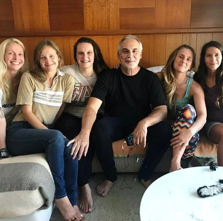 Birth Team sitting on a couch in a living room, smiling for the photo, with wood-paneled walls behind Dr. Stu Fischbein twin homebirth support with Katharine Deeb birth doula