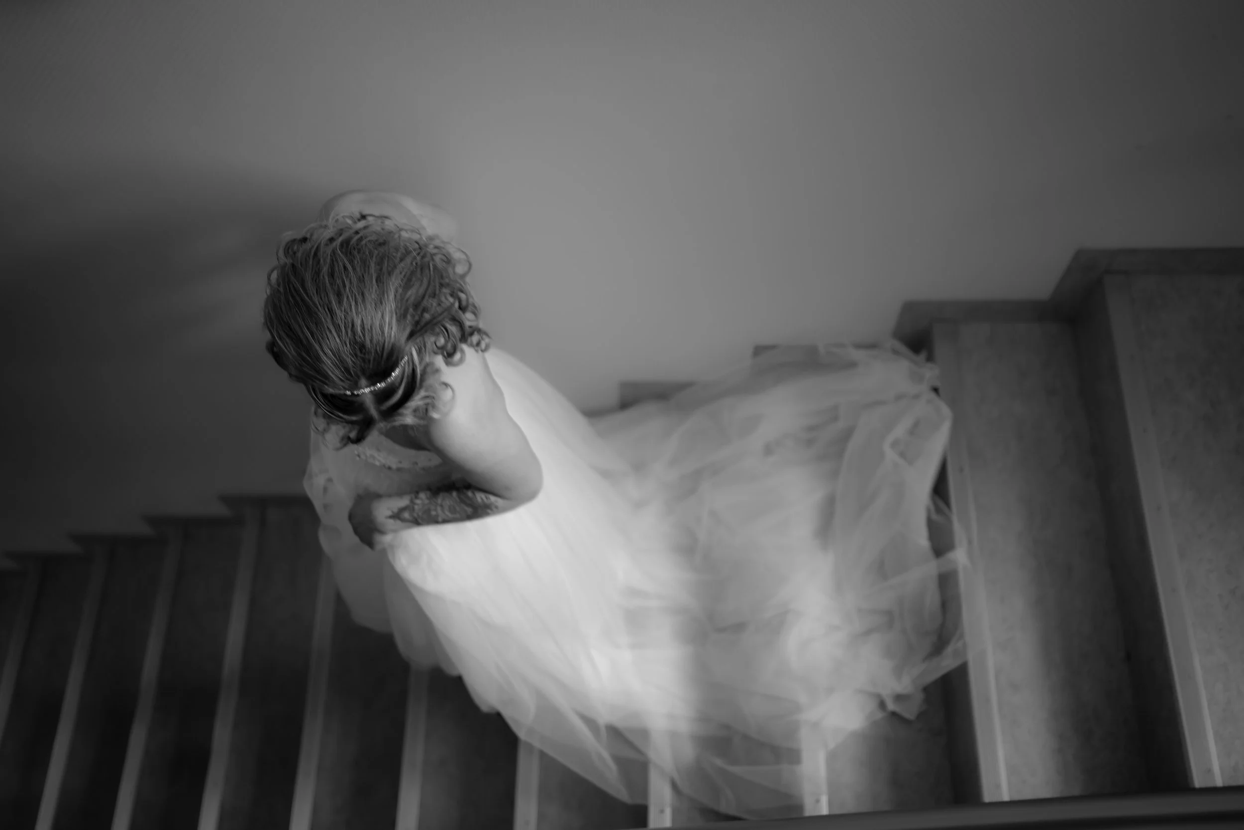 Eine Braut in einem weißen Kleid sitzt auf einer Treppe, gesehen von oben.